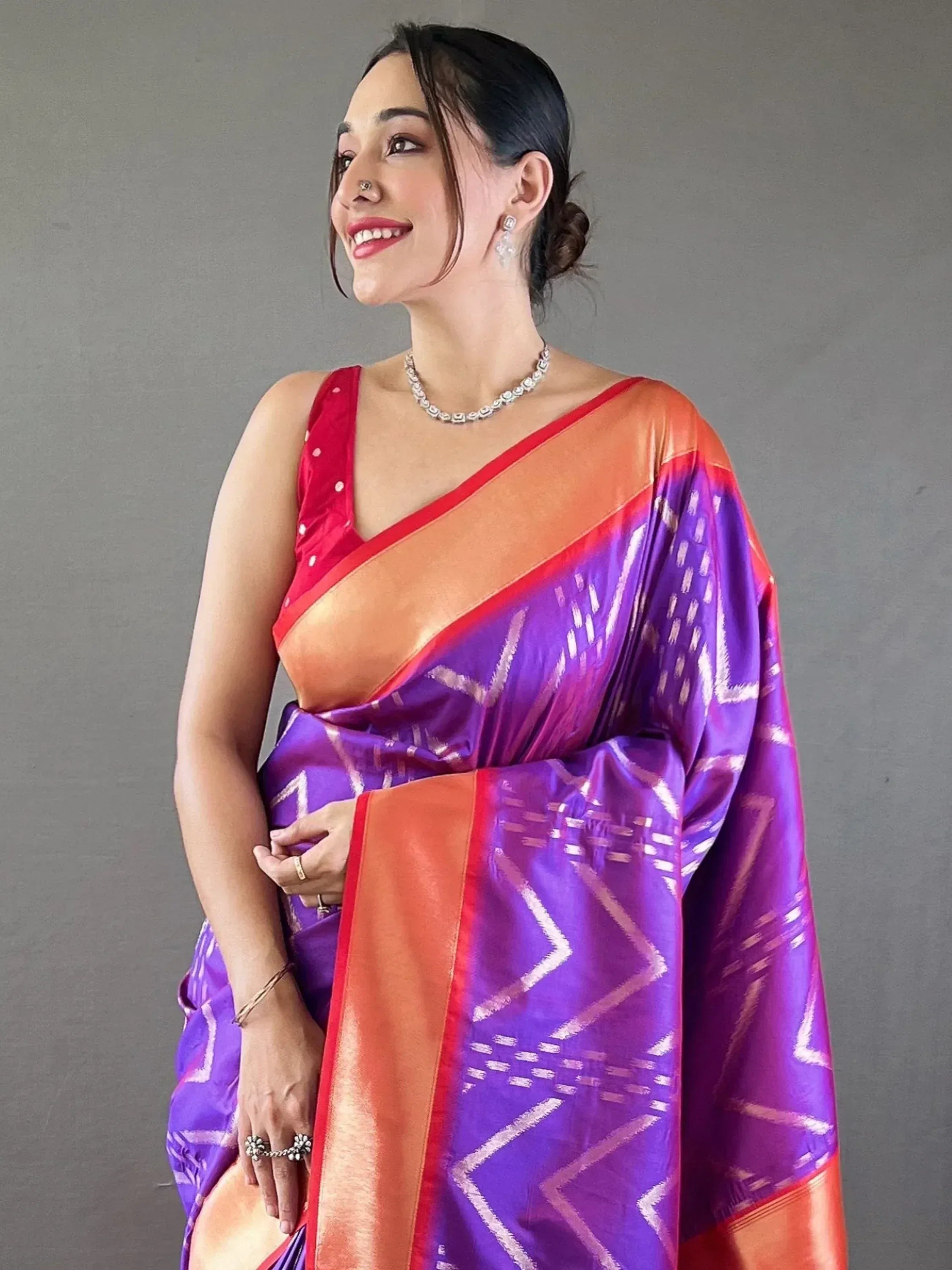 Woman in vibrant purple and orange ethnic saree with geometric patterns, perfect for Indian occasions