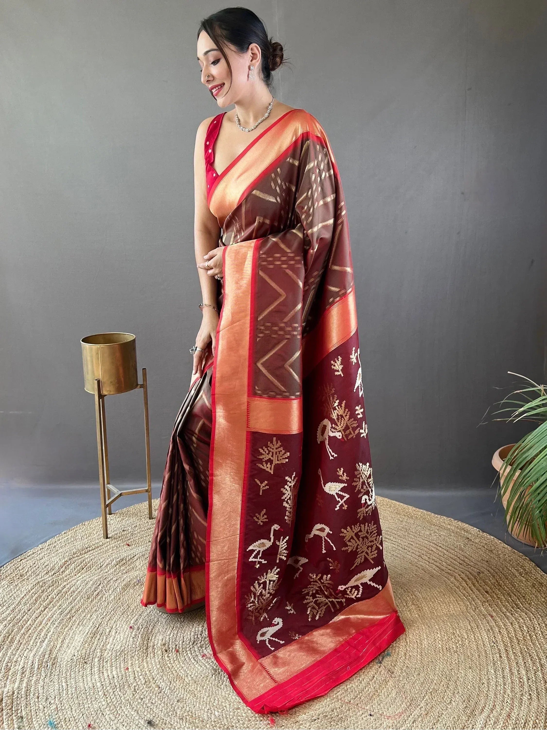 Woman in maroon and gold ethnic saree with bird and tree motifs, perfect for Indian occasions