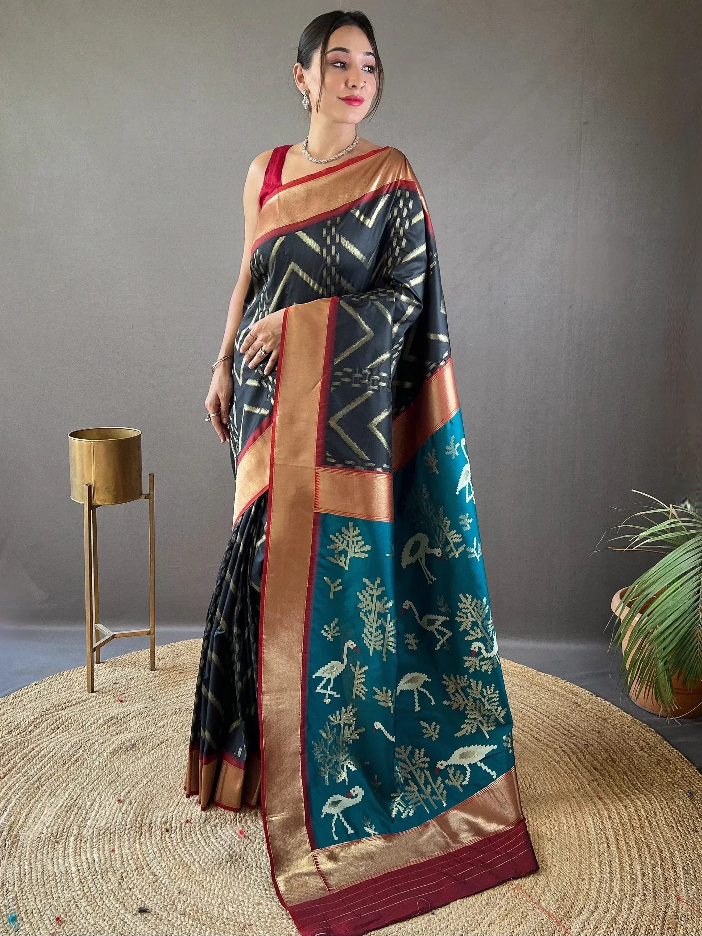 Woman wearing black and teal ethnic saree with gold bird and geometric patterns, perfect for Indian occasions
