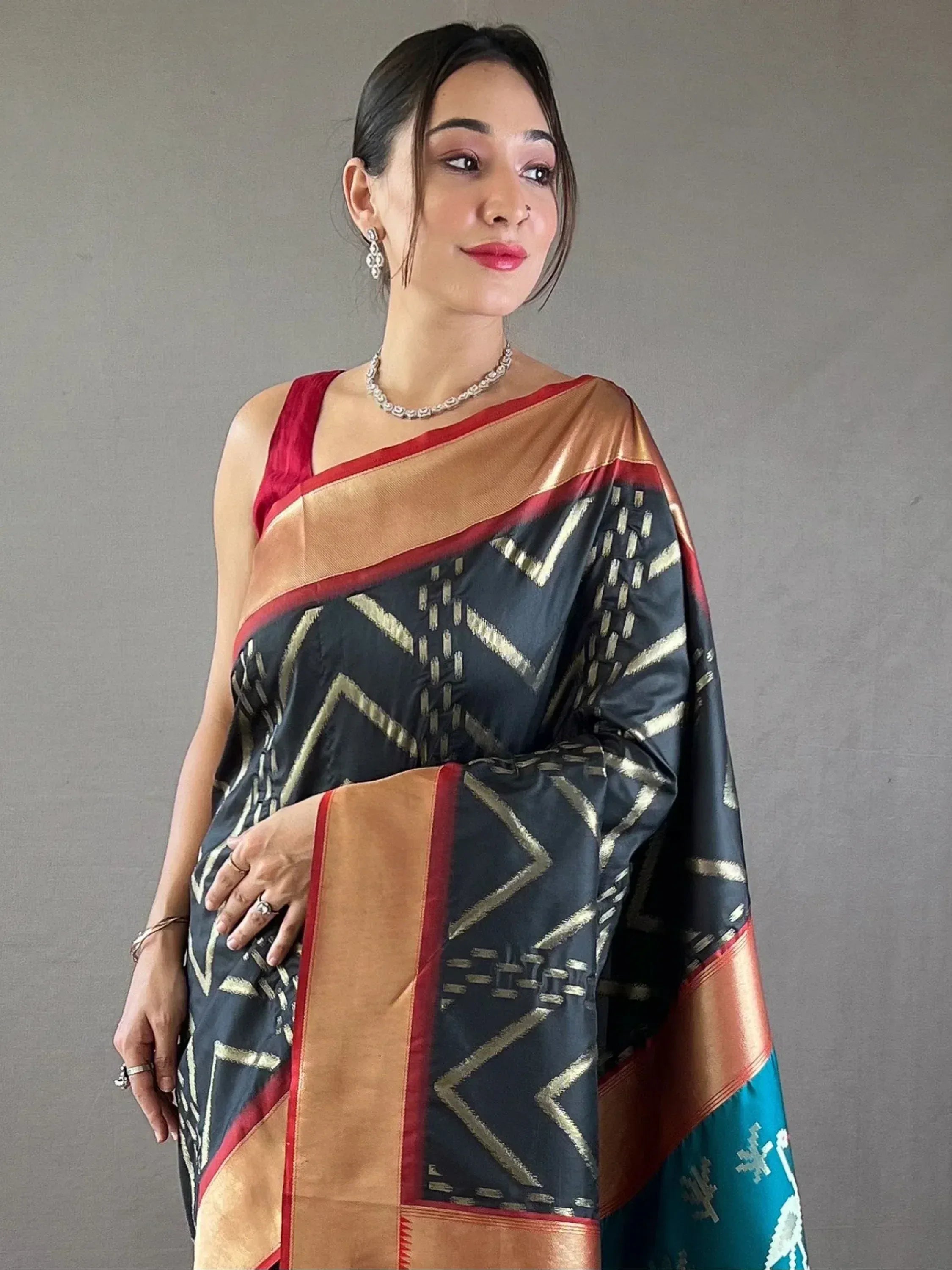 Woman wearing black and gold geometric print saree with red border, ethnic Indian wear