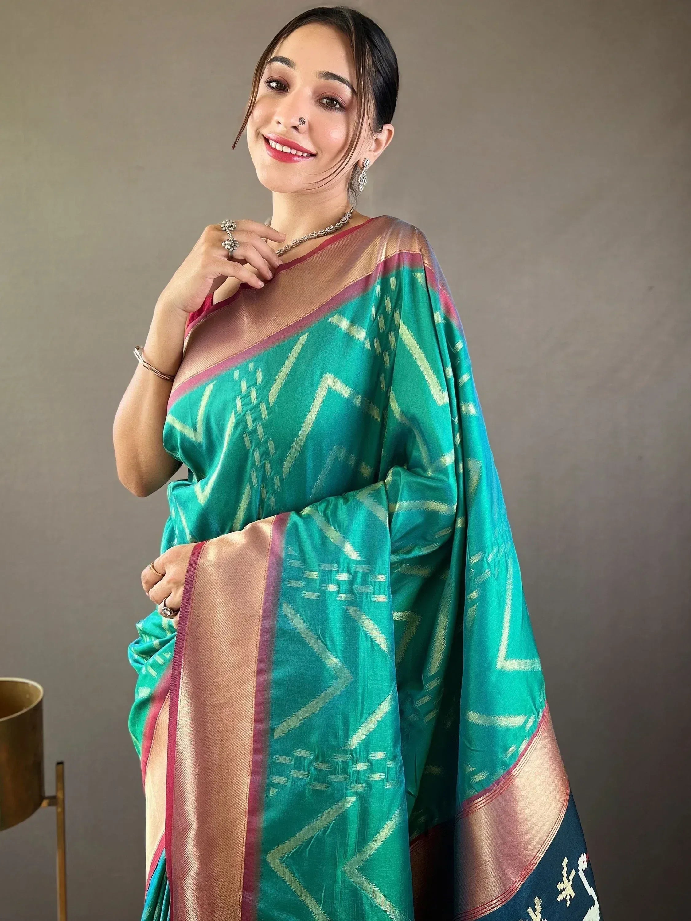 Woman in vibrant green ethnic saree with geometric weave and gold border, styled with traditional jewelry