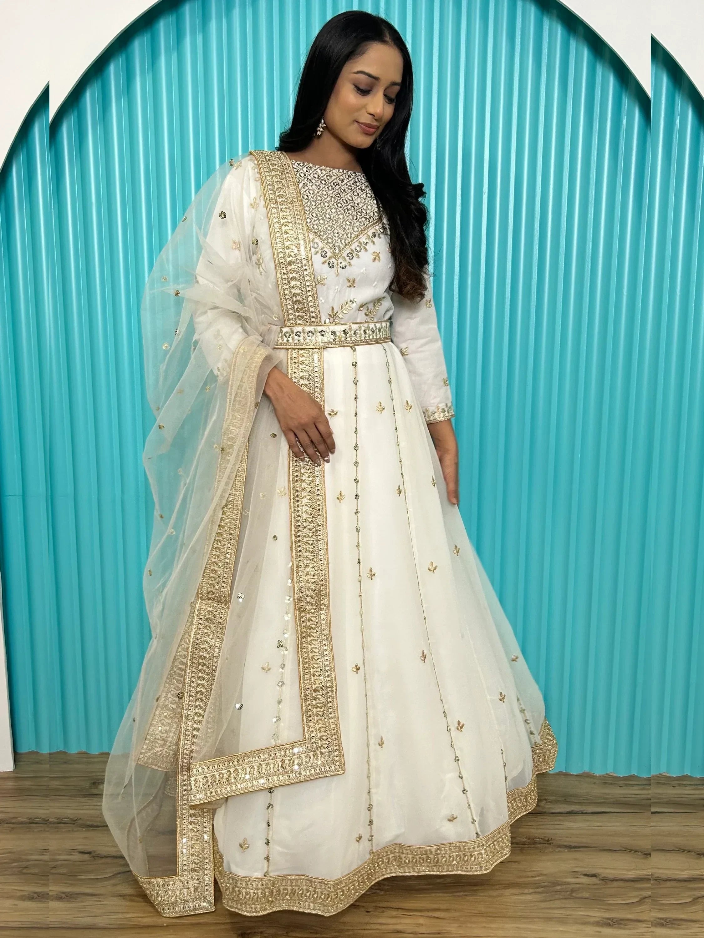 Woman wearing white and gold embroidered Indian ethnic gown with dupatta