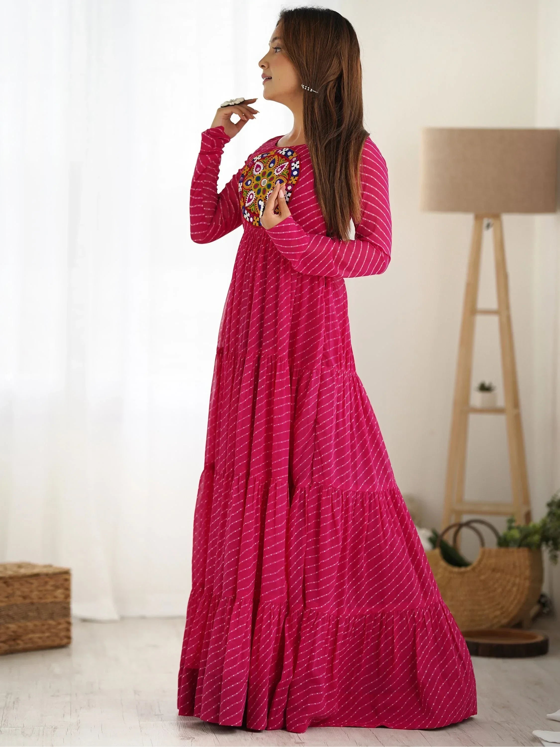 Woman in magenta Indian ethnic gown with mirror work embroidery, standing indoors