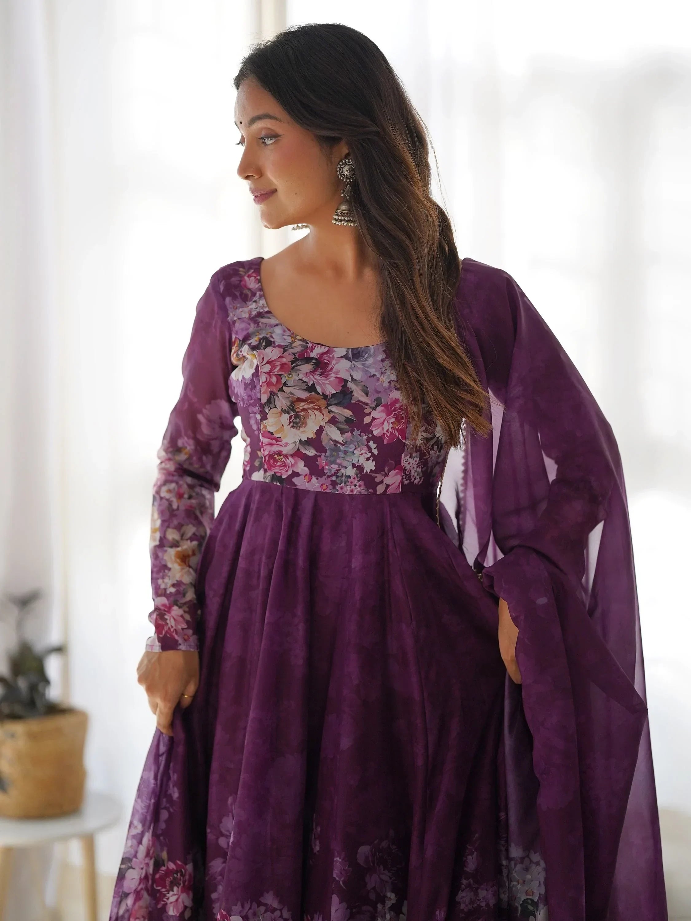 Woman in purple floral ethnic gown with dupatta, wearing silver jhumka earrings