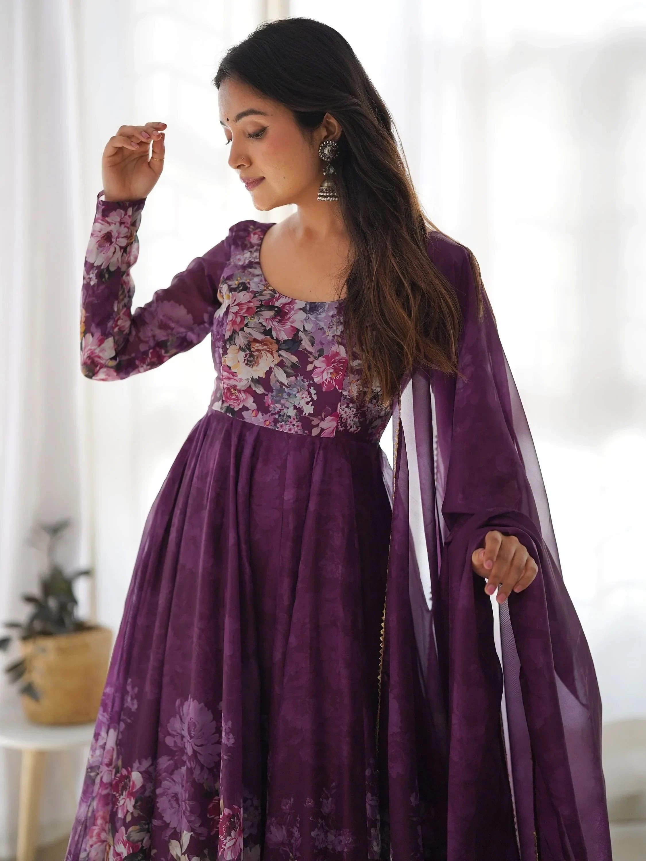 Woman in purple floral ethnic gown with dupatta and silver jhumka earrings indoors