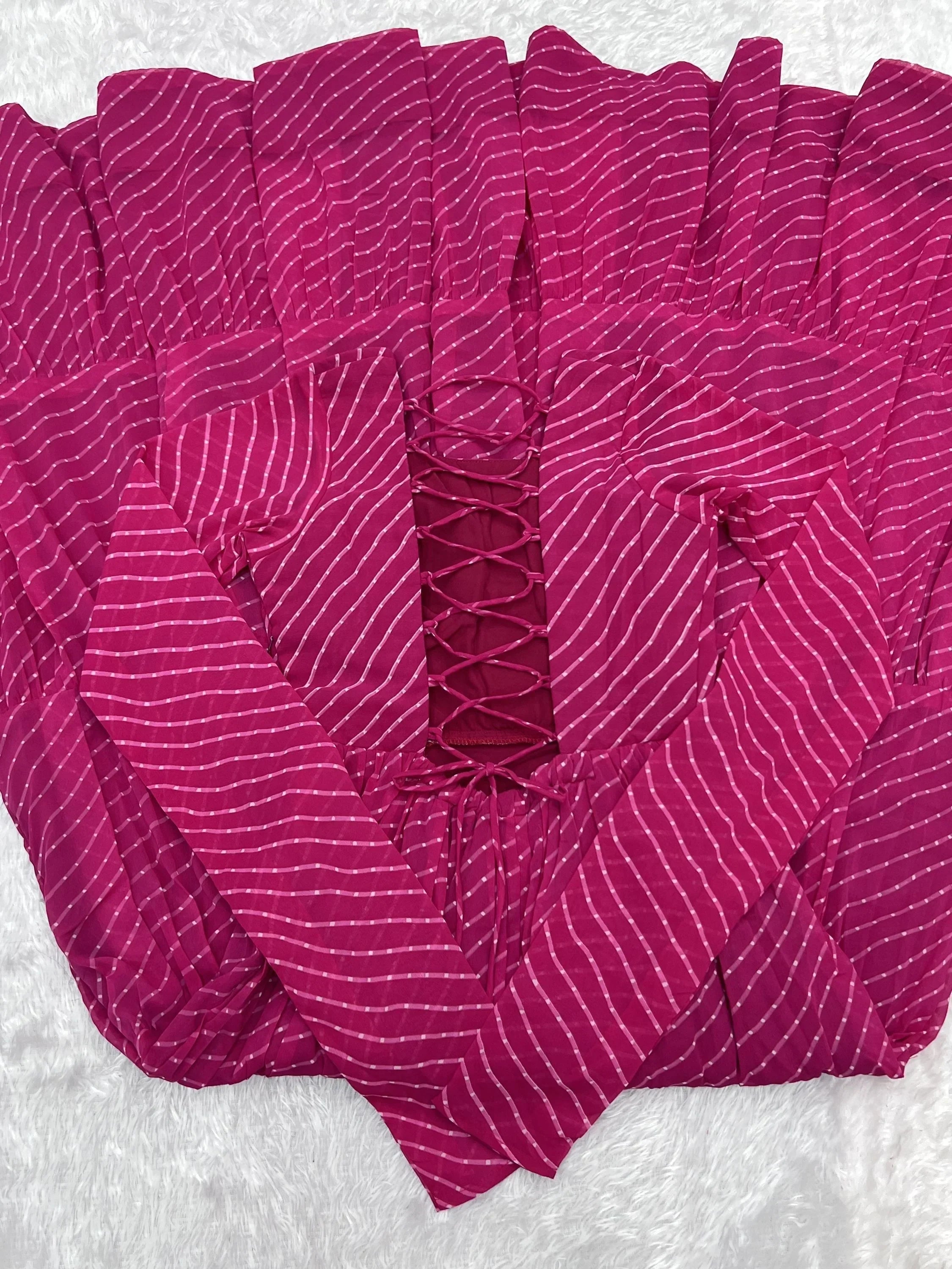 Pink striped ethnic dress with lace-up front and long sleeves on white fur background