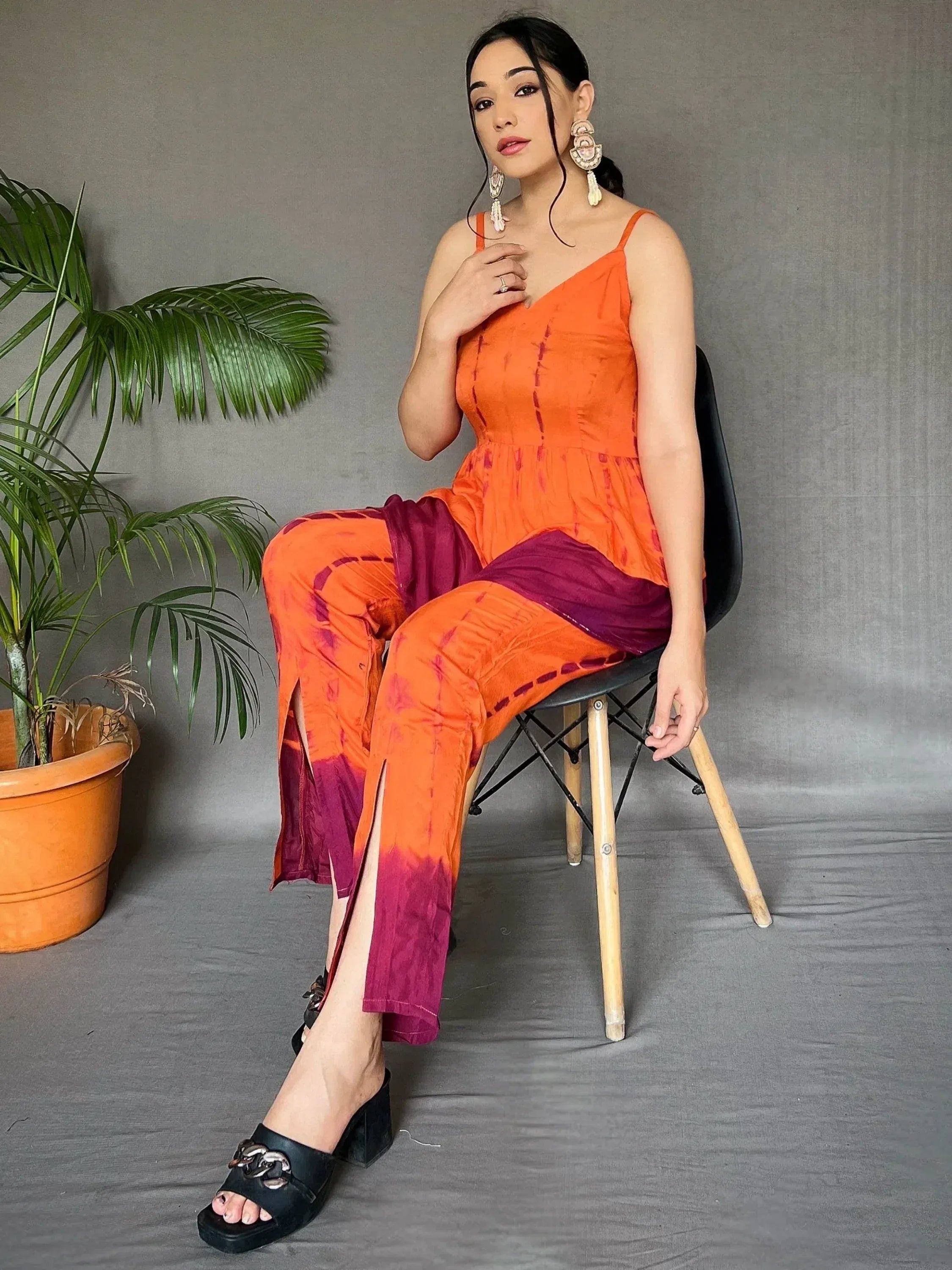 Orange and purple tie-dye ethnic pants with matching top, styled with statement earrings and black heels