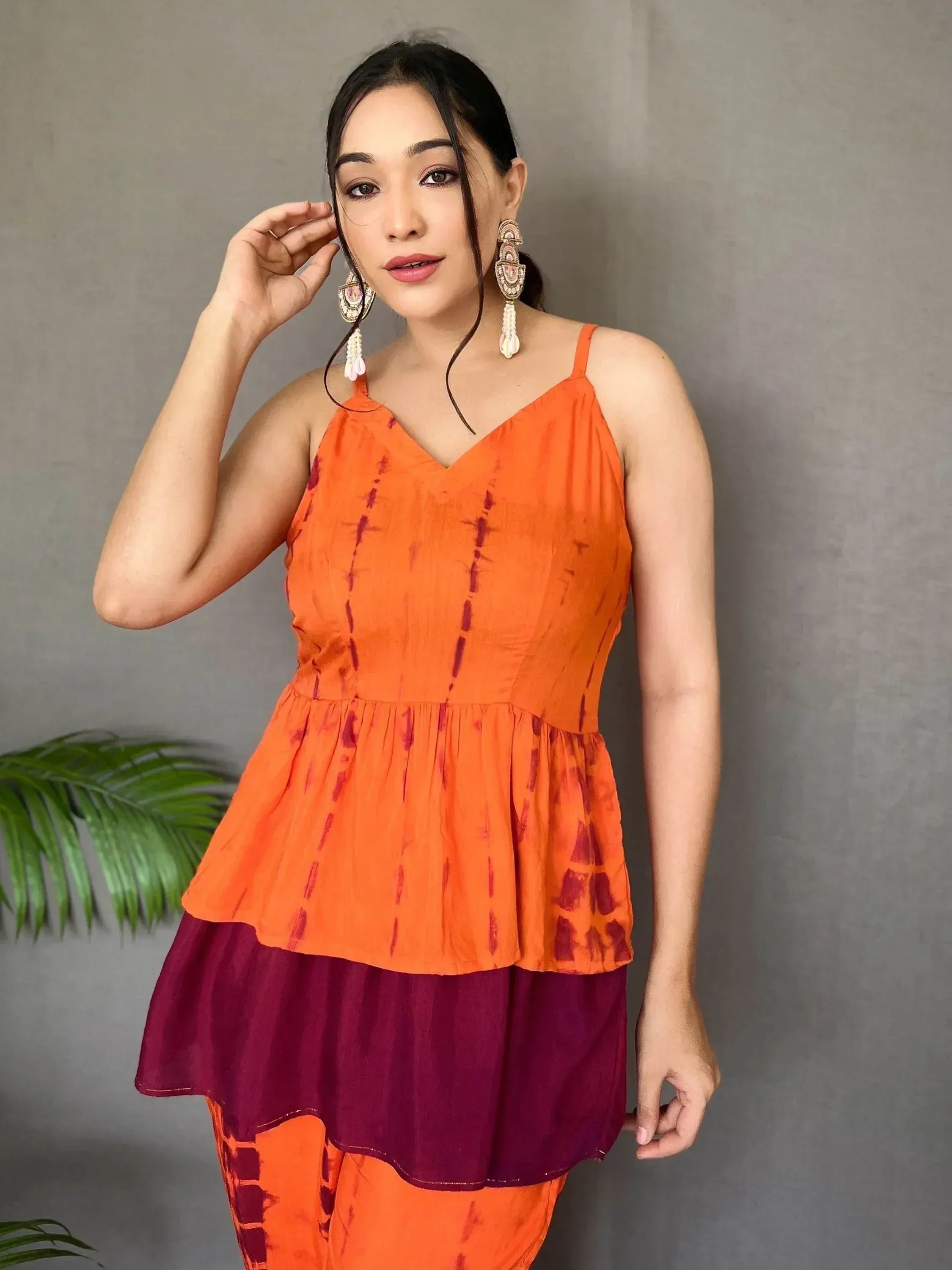 Orange tie-dye ethnic top with maroon peplum and matching palazzo pants, styled with statement earrings