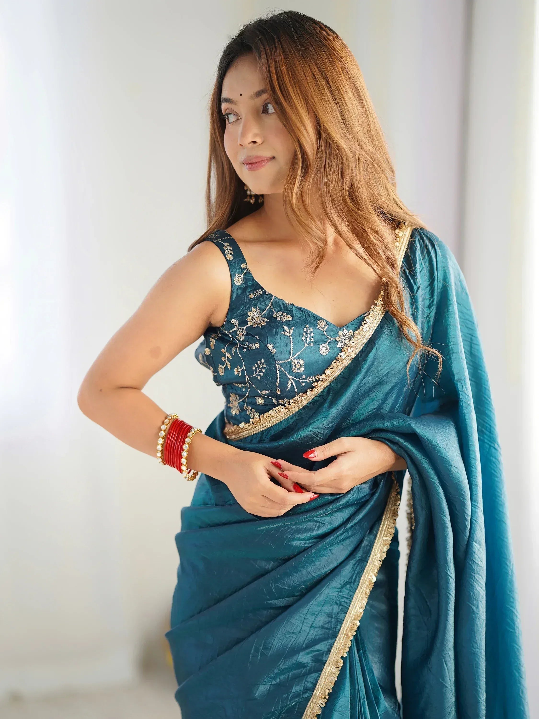 Teal blue saree with gold embroidery and floral blouse, styled with red bangles for Indian ethnic wear