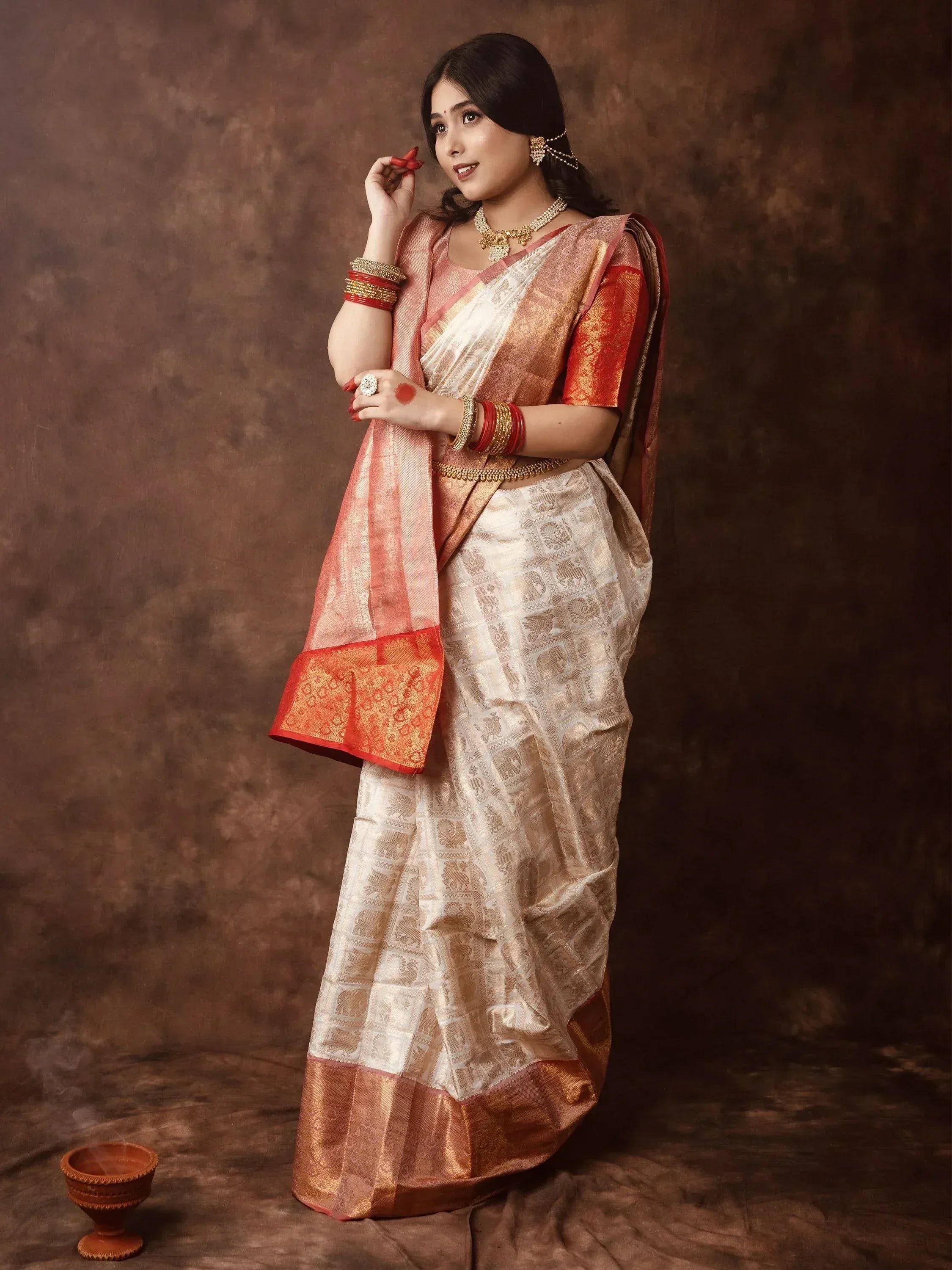 Woman in elegant white and gold Banarasi saree with red border, traditional Indian ethnic wear