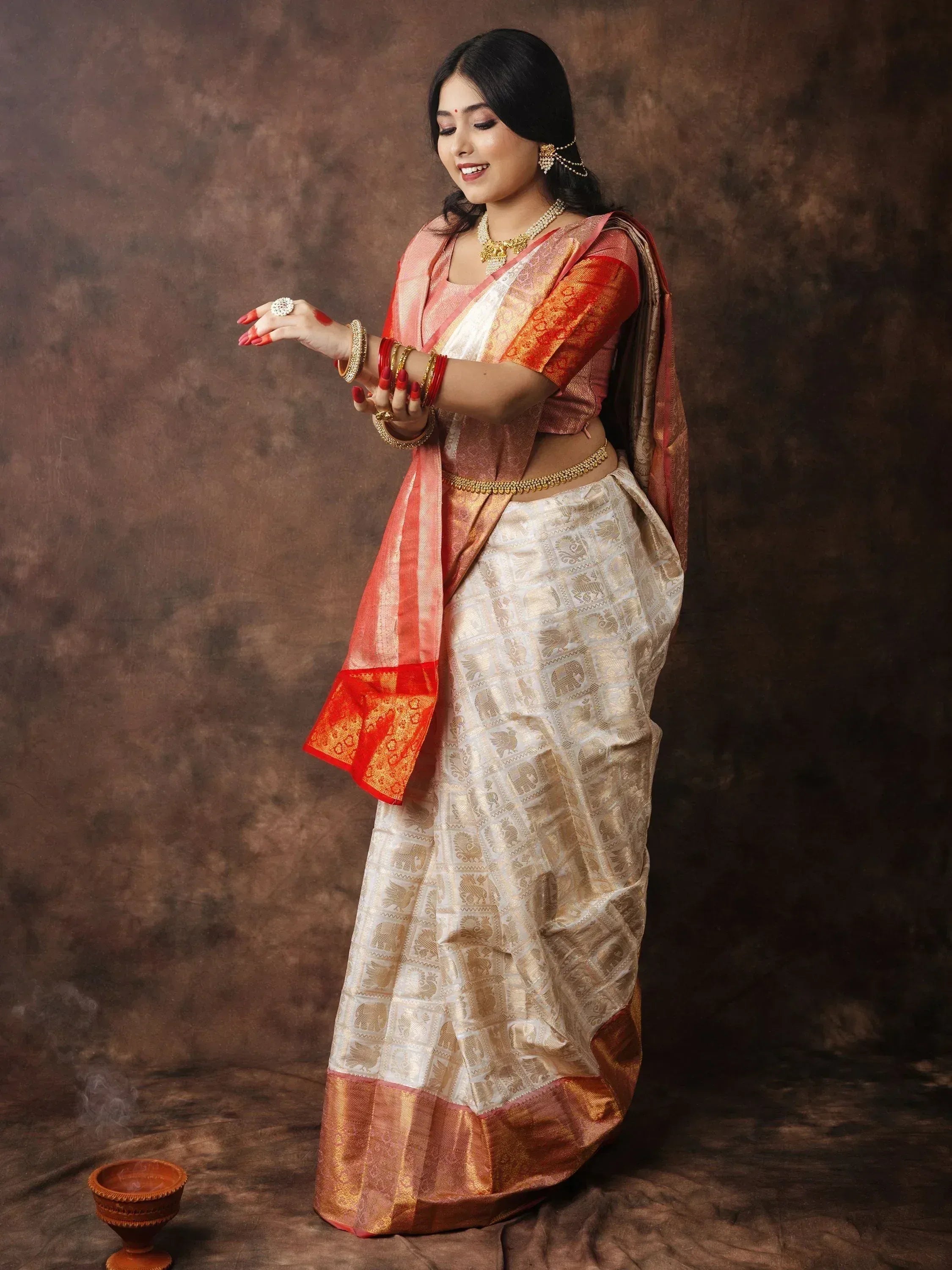 Woman in elegant white and gold saree with red border, traditional Indian ethnic wear, festive look