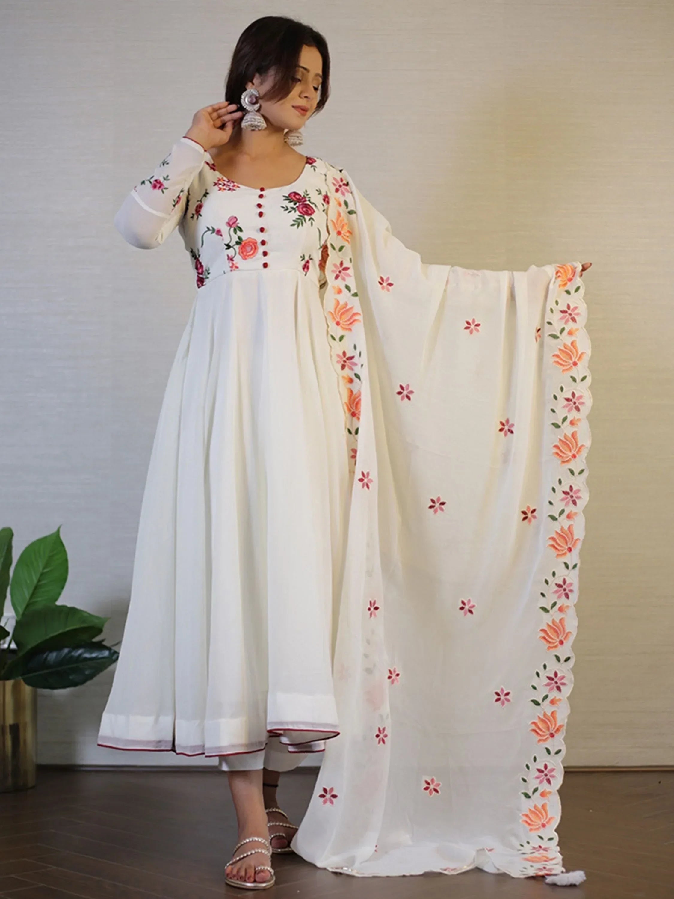 Woman wearing white embroidered Anarkali suit with floral dupatta and statement earrings