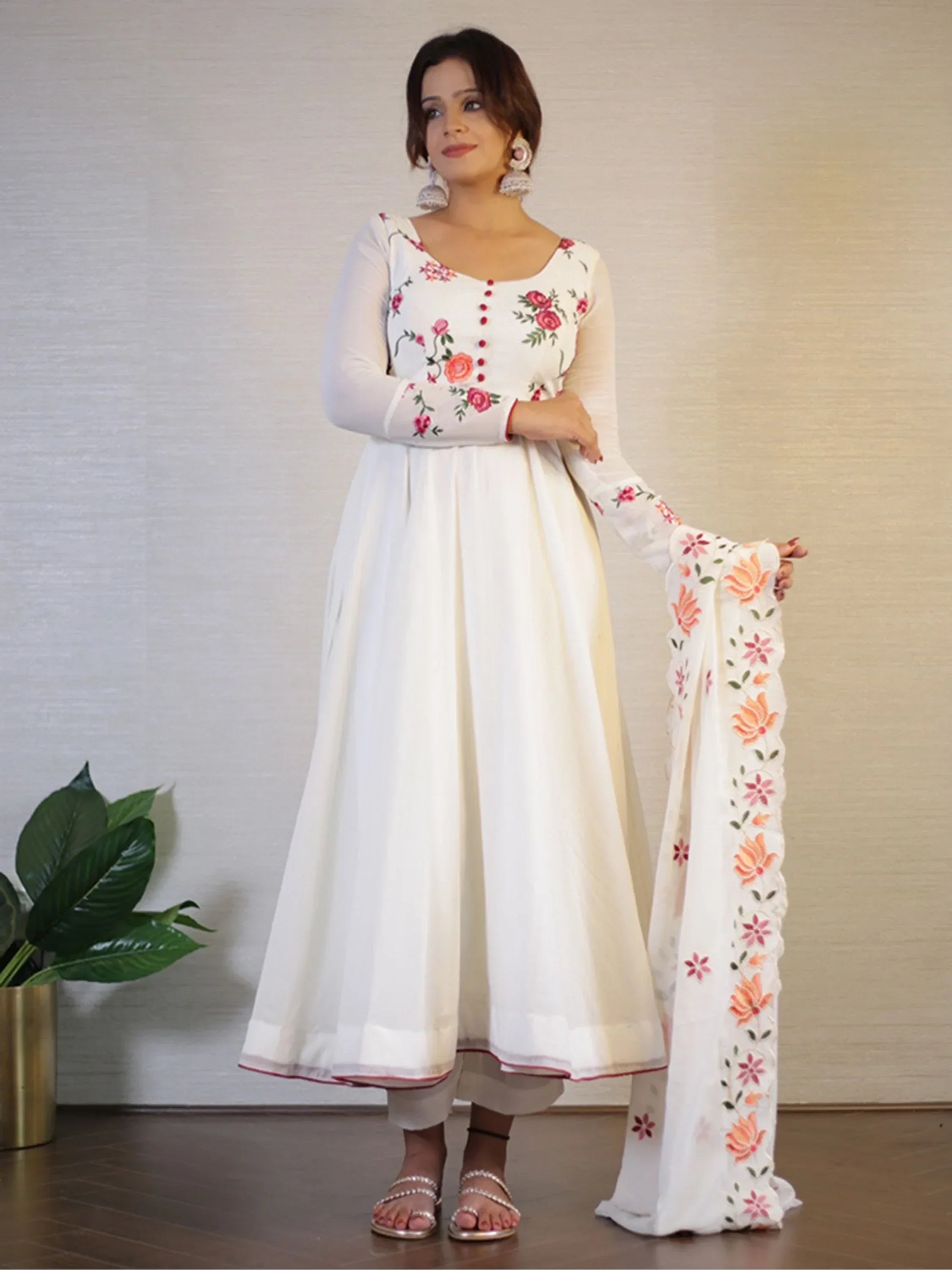 Woman wearing white embroidered Anarkali suit with floral dupatta and statement earrings
