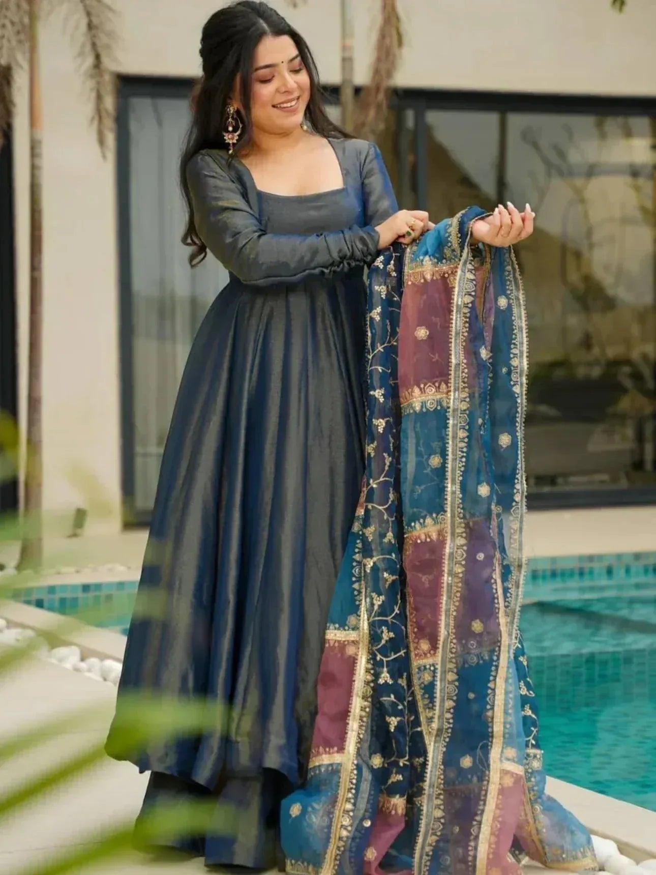 Woman in navy blue ethnic gown with embroidered dupatta, poolside setting