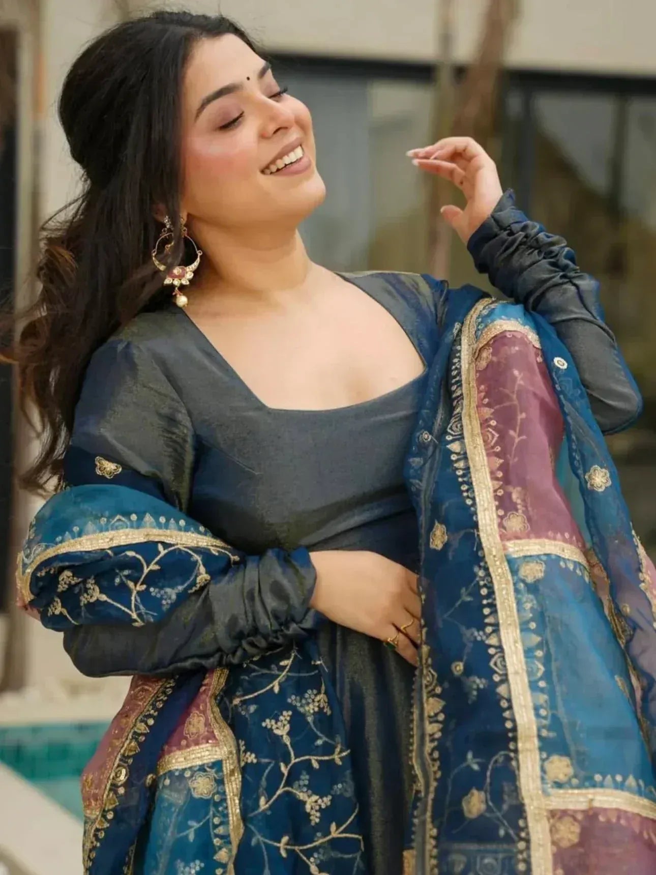 Woman in elegant blue ethnic gown with gold embroidery and matching dupatta, perfect for Indian occasions.