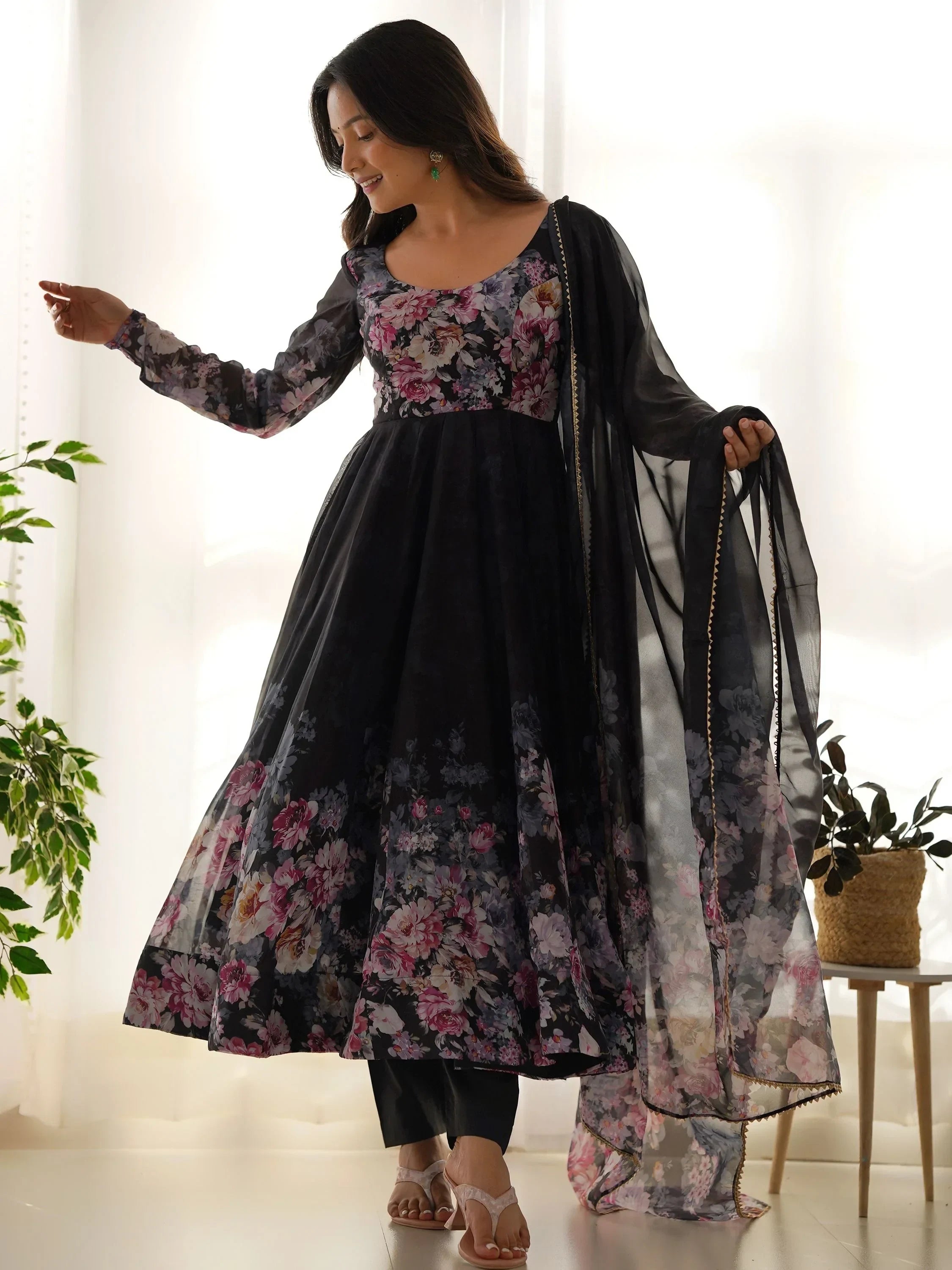Woman wearing a black floral printed Anarkali suit with matching dupatta in a bright room
