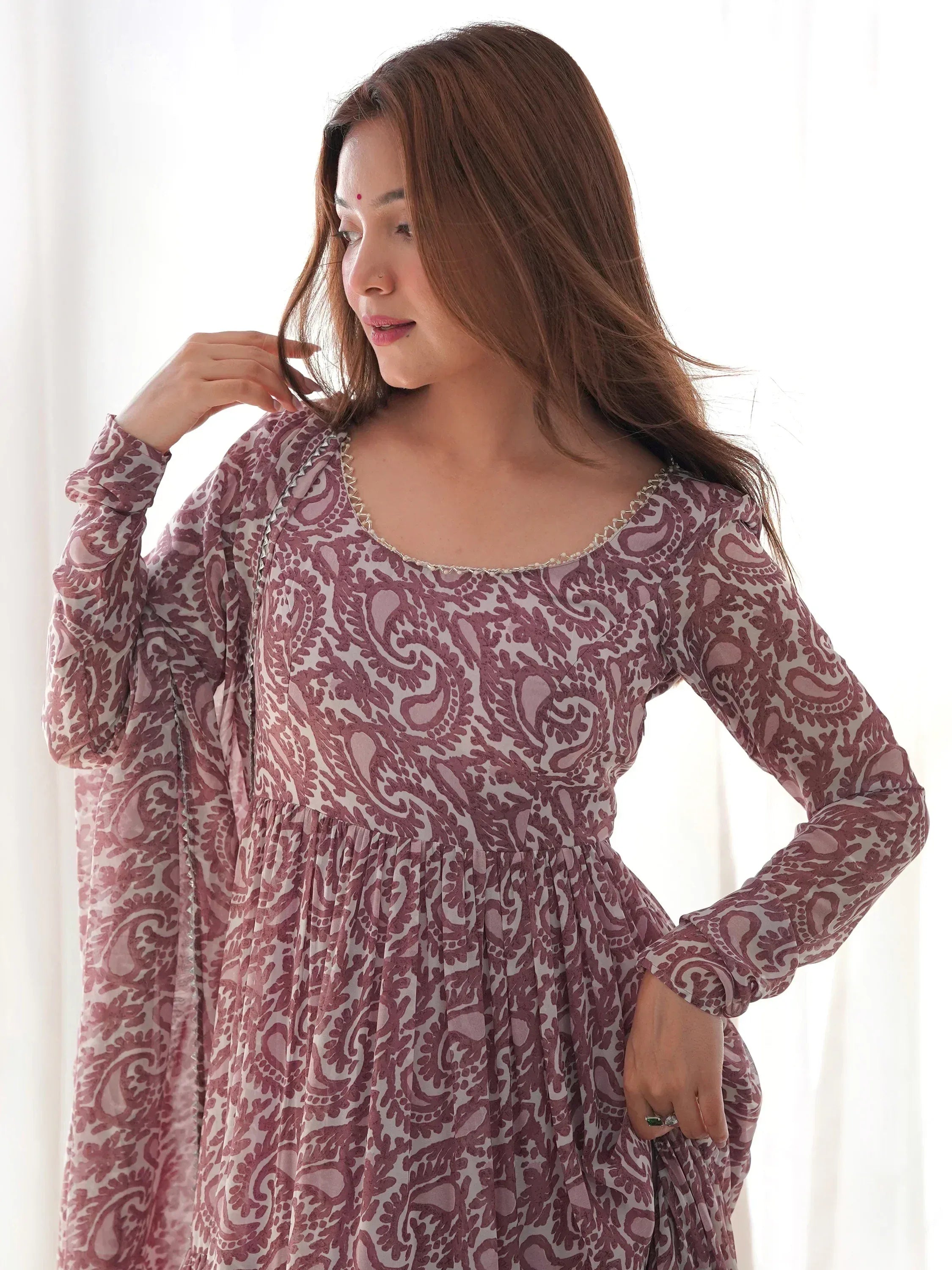 Woman wearing mauve ethnic printed salwar kameez with sheer dupatta, indoors