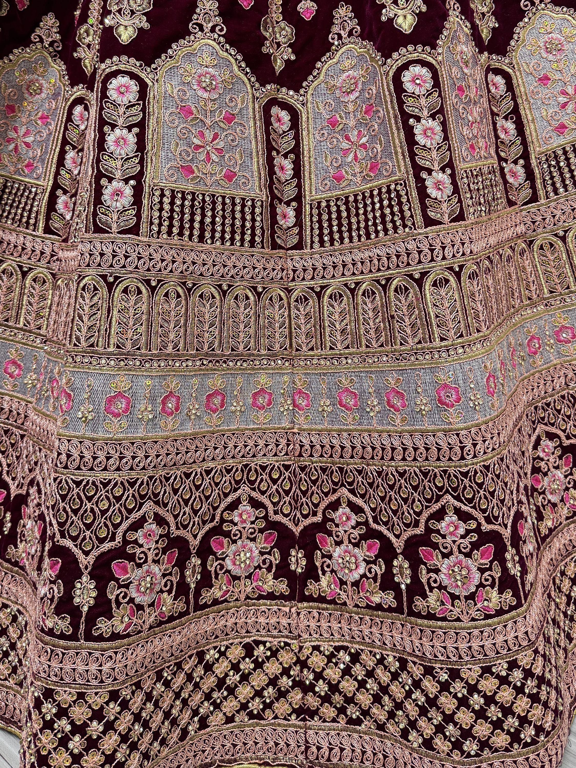 Richly embroidered maroon ethnic gown with floral and geometric patterns in gold and pink