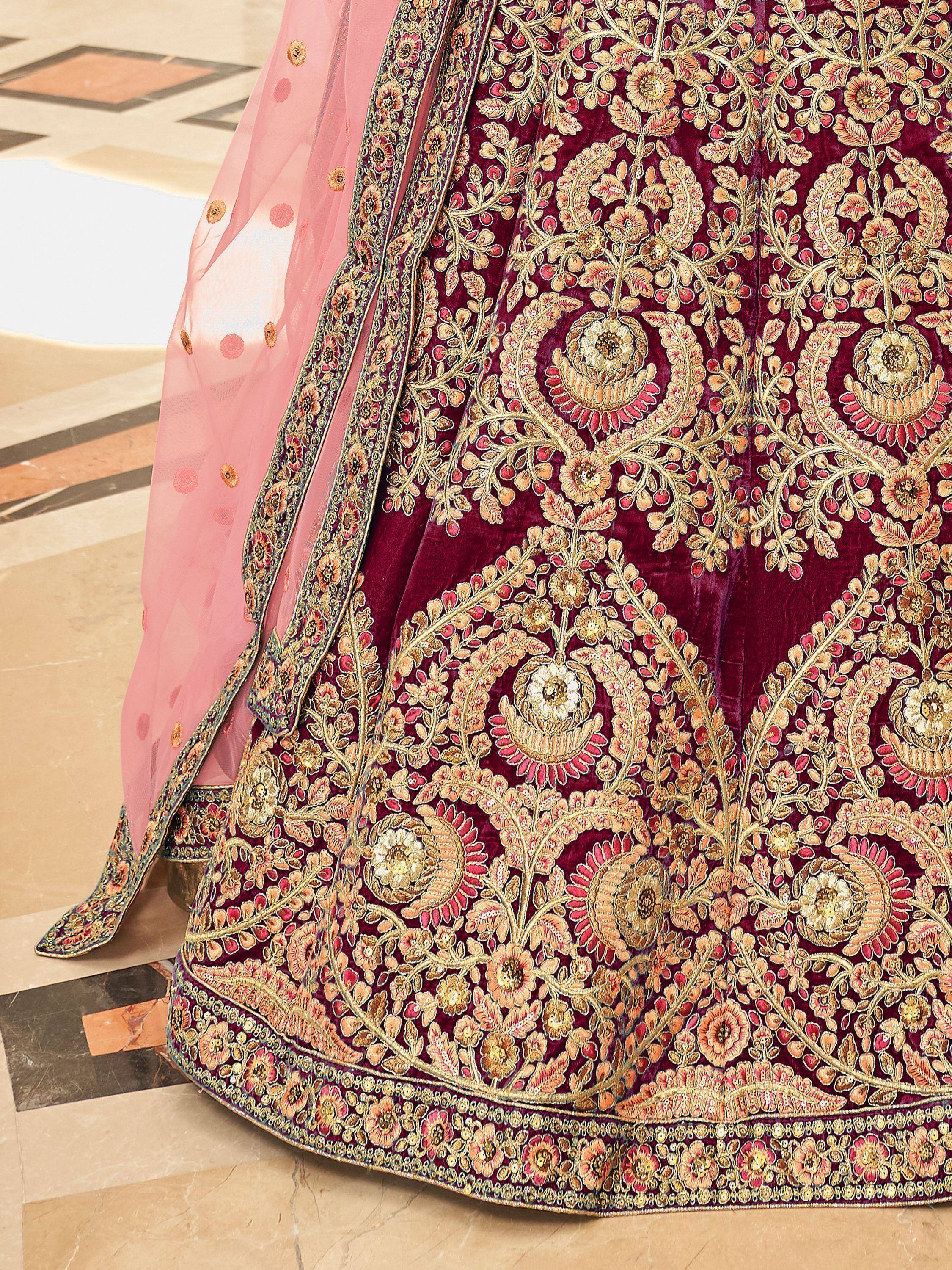 Rich maroon velvet lehenga with intricate gold floral embroidery and pink dupatta, ideal for Indian weddings.