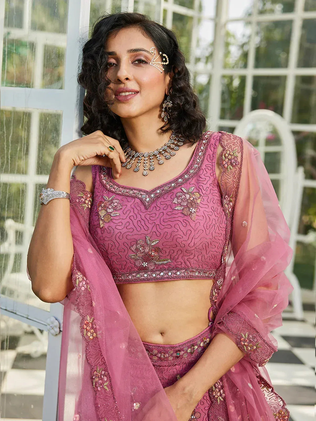 Pink embroidered lehenga choli with floral motifs and sheer dupatta, styled with traditional jewelry