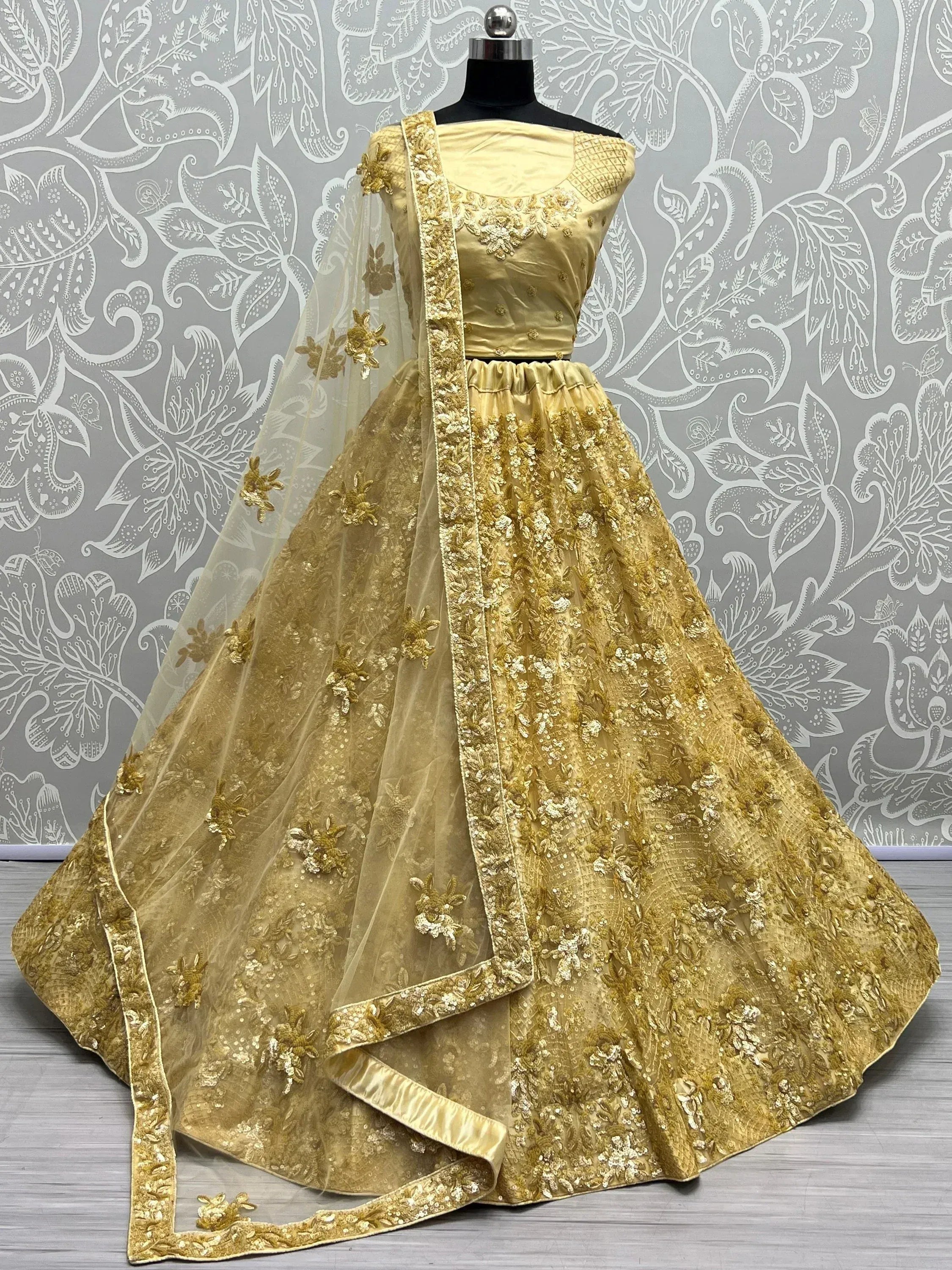 Golden embroidered lehenga choli with floral motifs and sheer dupatta, perfect for Indian ethnic wear events.