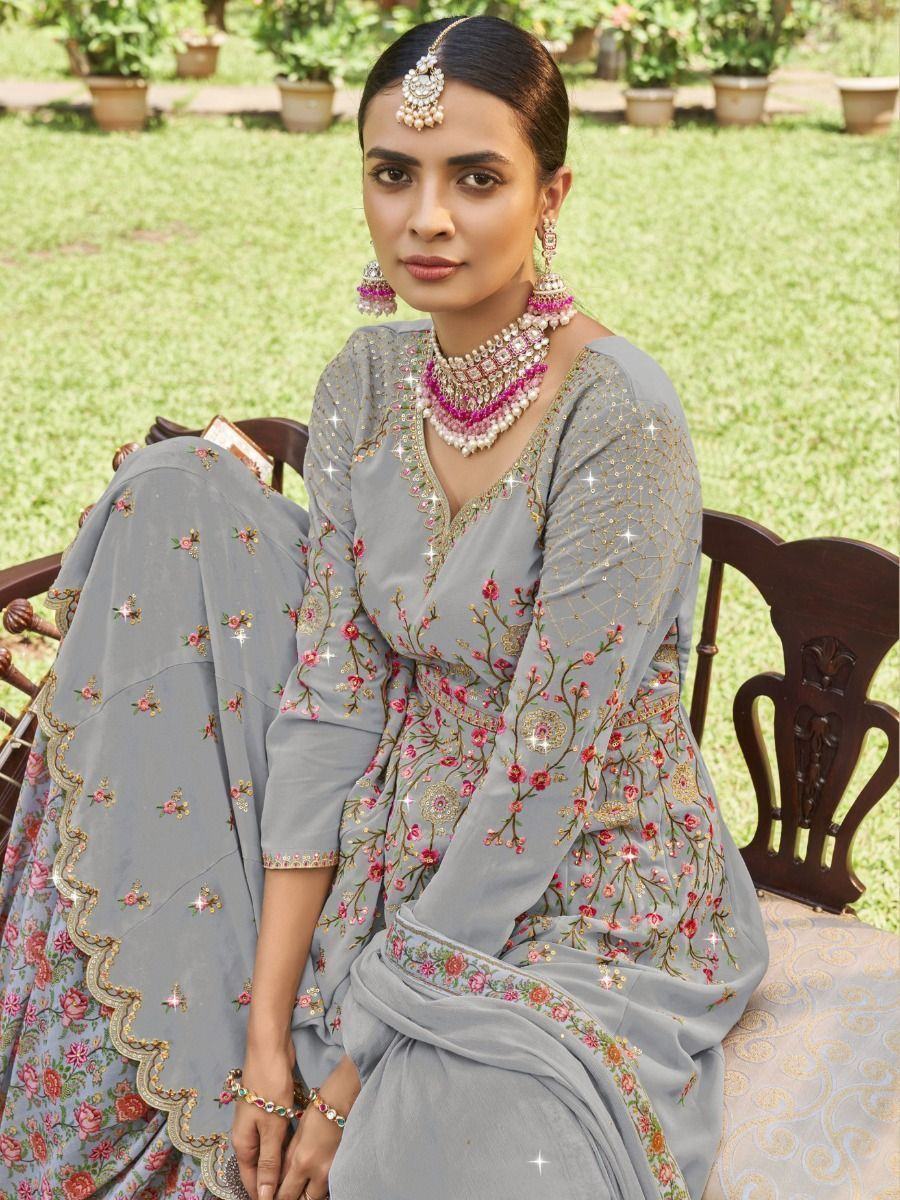 Woman in grey floral embroidered lehenga choli with pink jewelry, seated outdoors