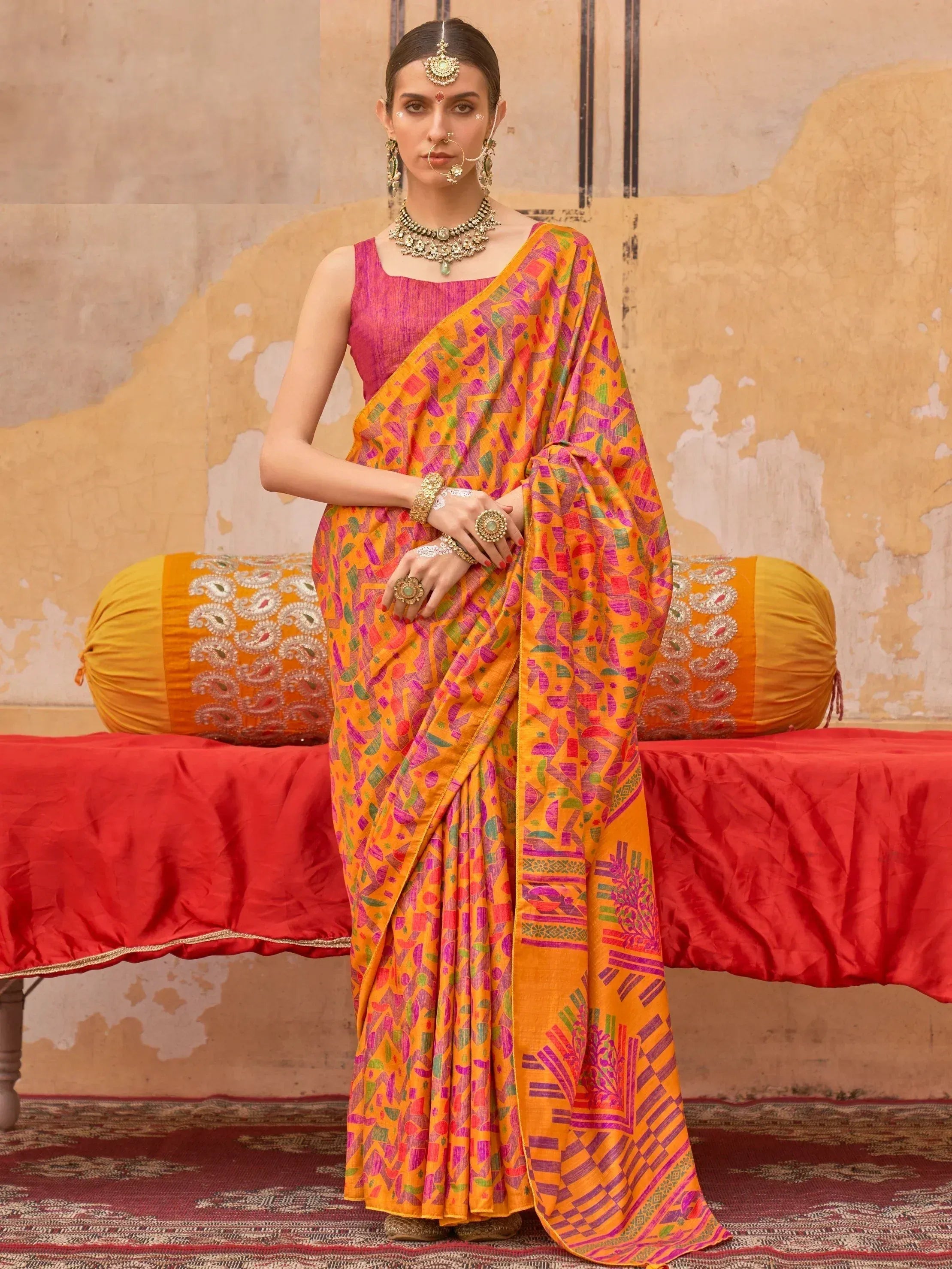 Vibrant orange and pink printed saree with geometric patterns, paired with traditional Indian jewelry for ethnic wear.