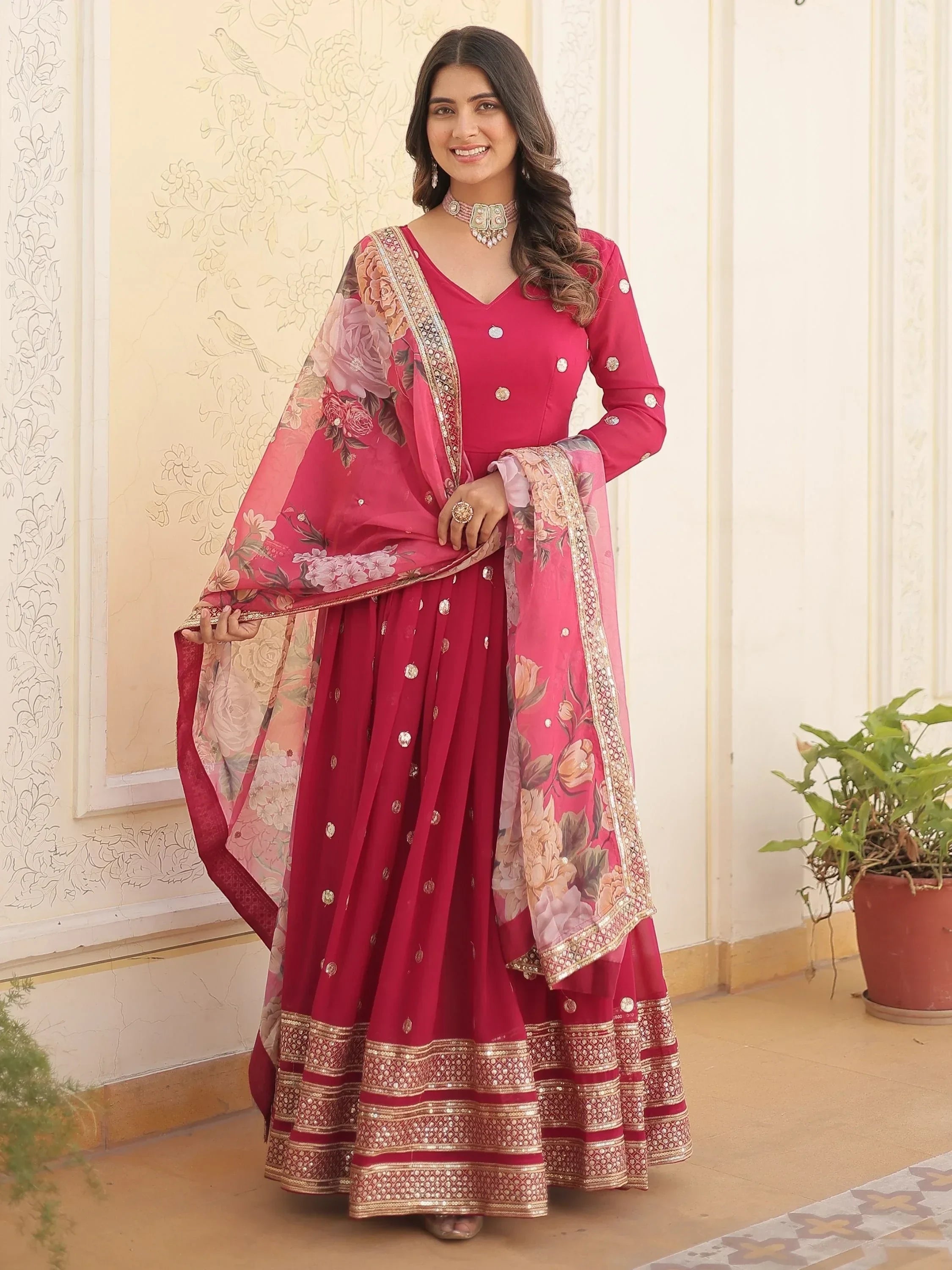 Woman in pink designer lehenga choli with floral dupatta and gold embroidered borders