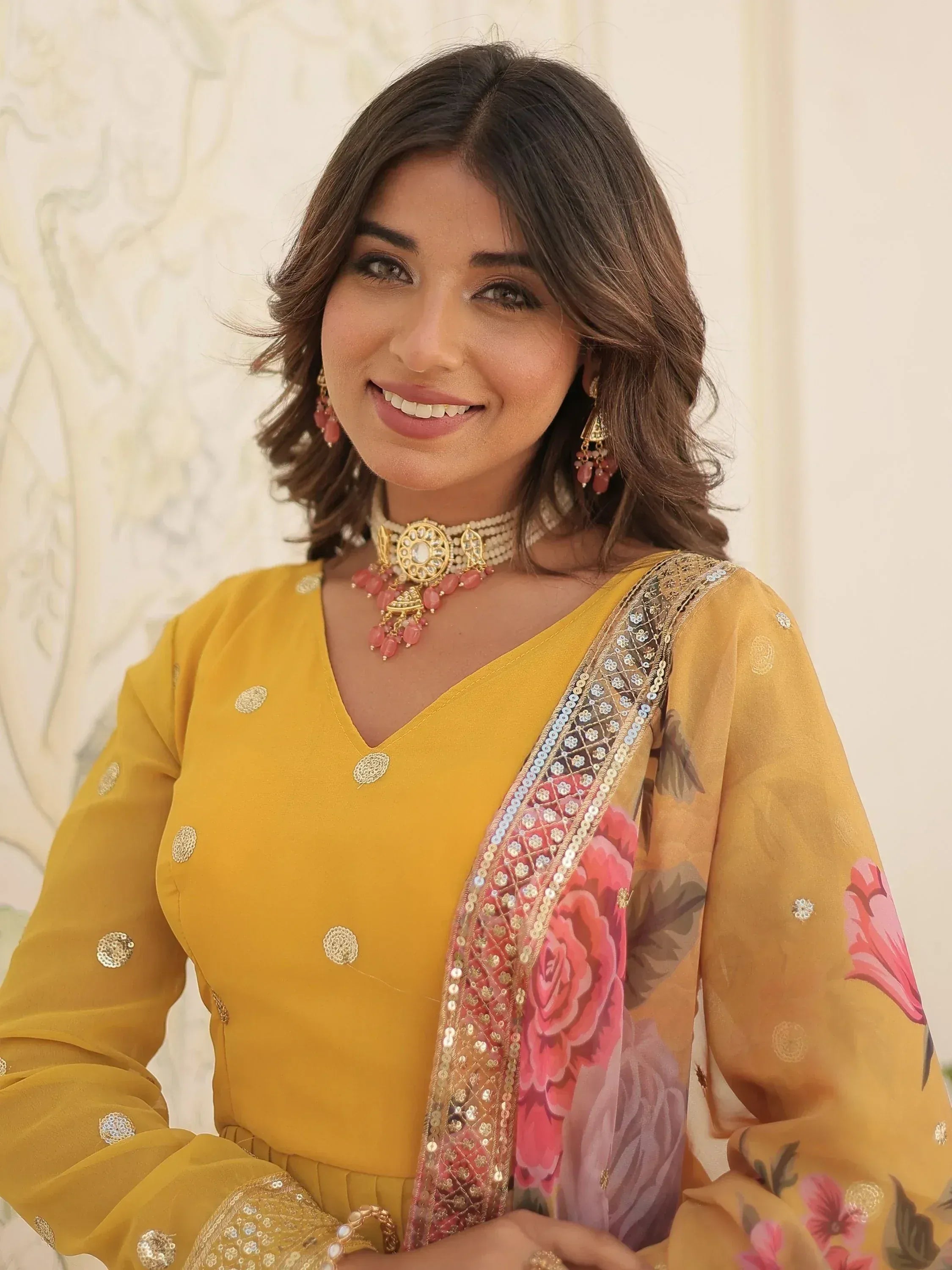 Yellow floral salwar kameez with sequin embroidery and pink dupatta, styled with traditional jewelry