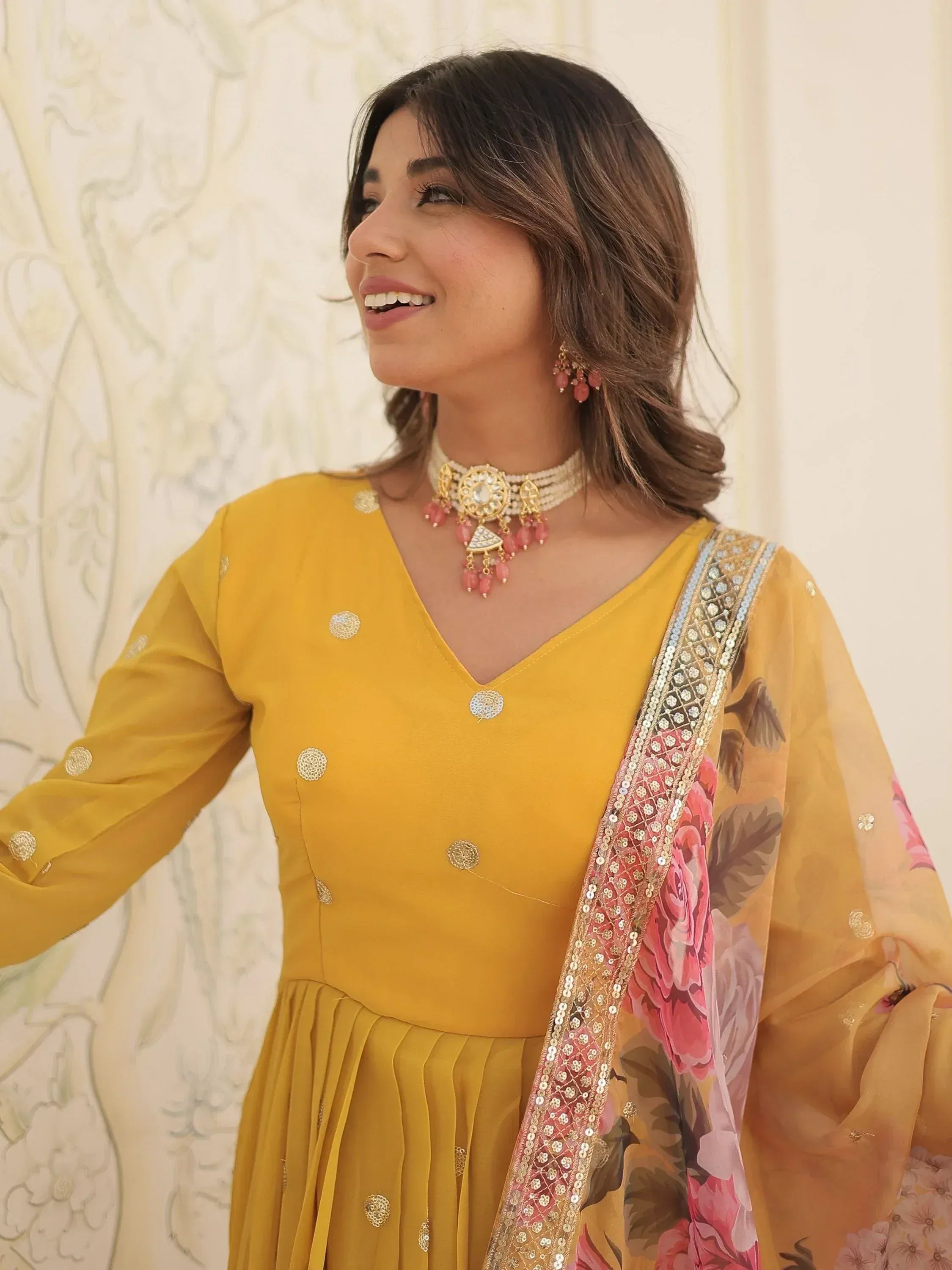 Yellow ethnic salwar kameez with floral dupatta and gold embroidery, paired with pink jewelry