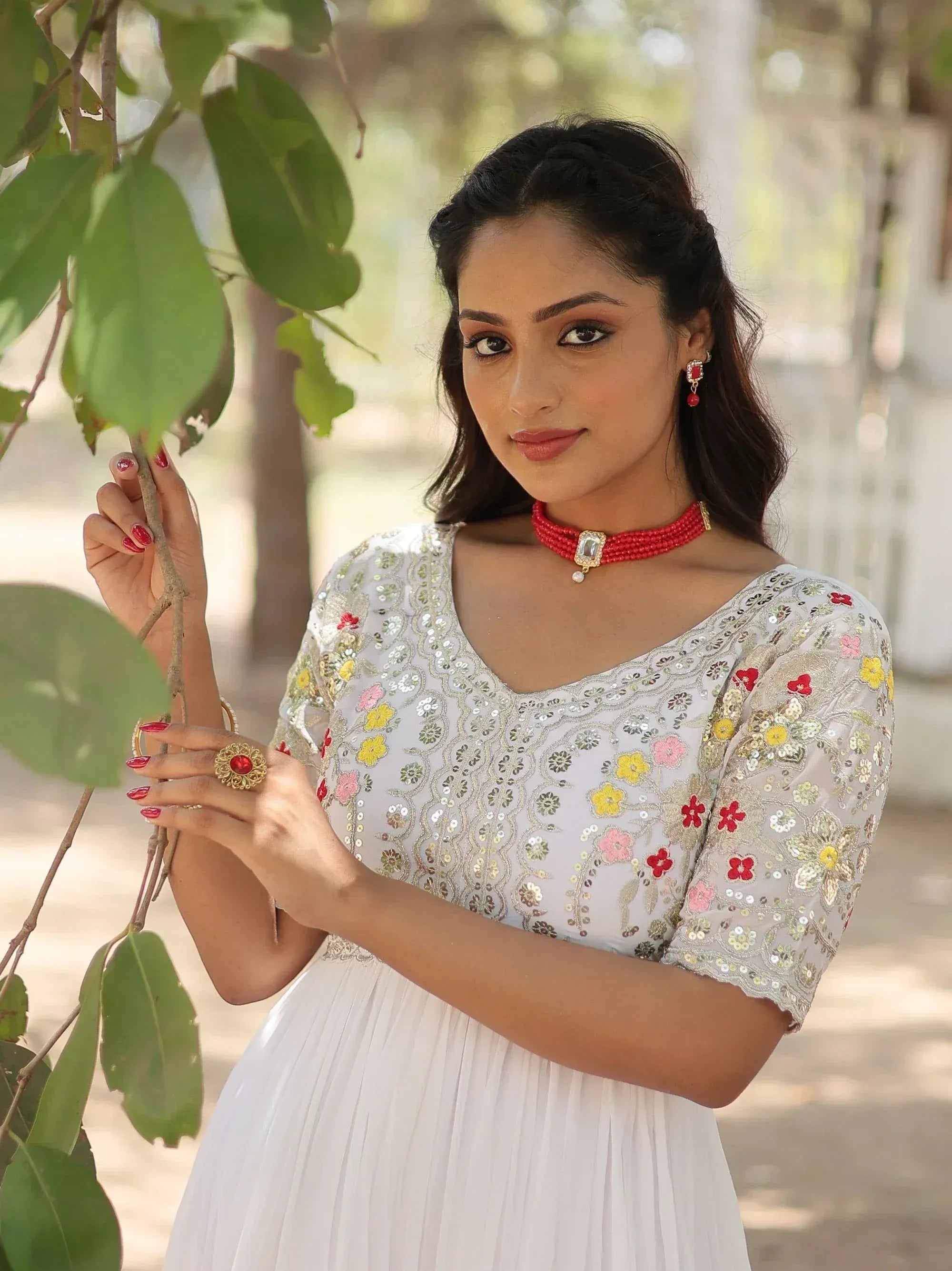 White floral embroidered ethnic gown with red jewelry, perfect for Indian occasions