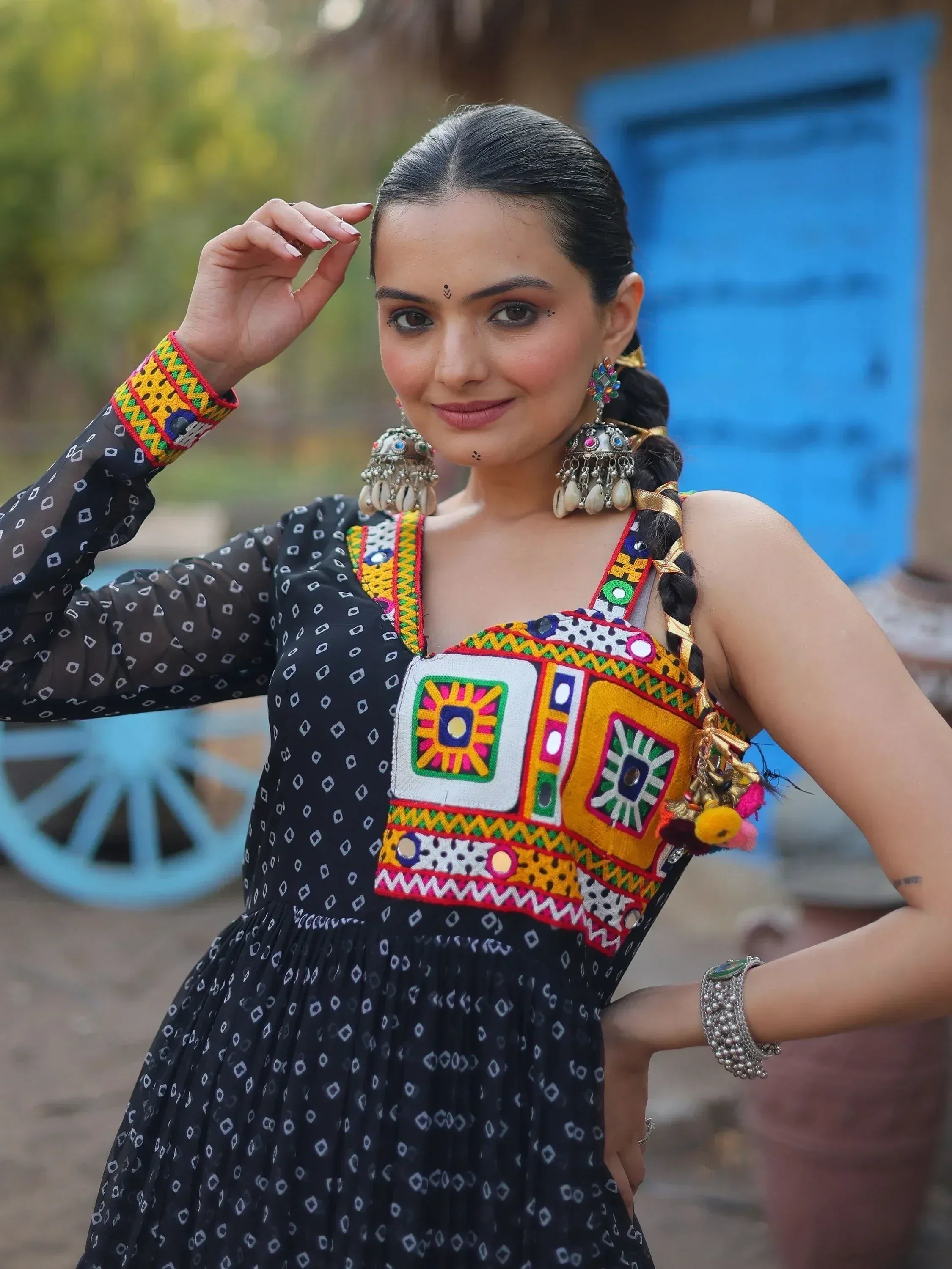 Woman in black printed ethnic gown with colorful mirror work and traditional jewelry, perfect for Indian festive wear.