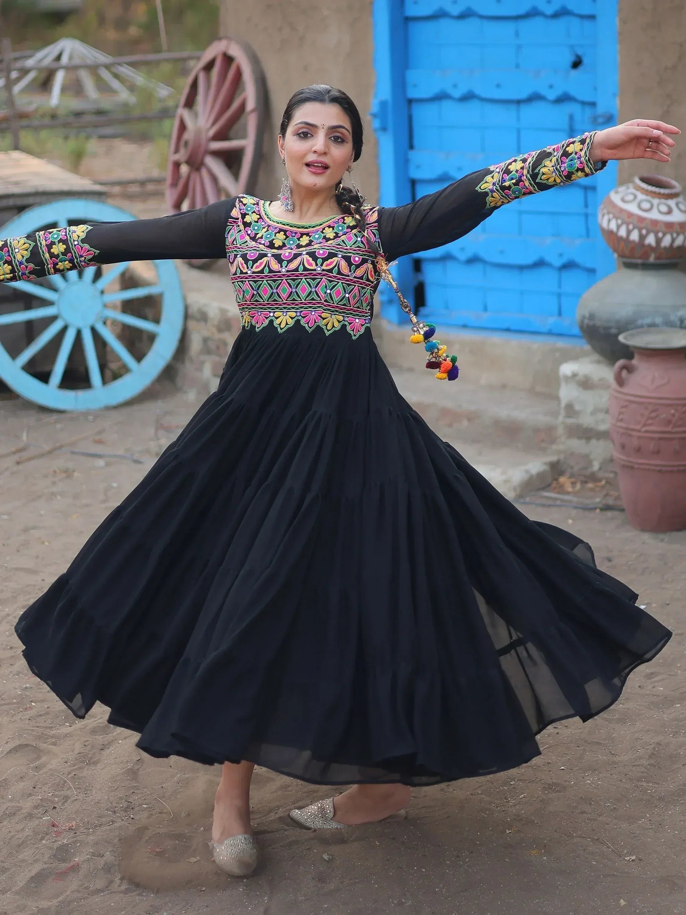 Woman twirling in black embroidered ethnic gown with colorful floral motifs, perfect for Indian festive occasions.