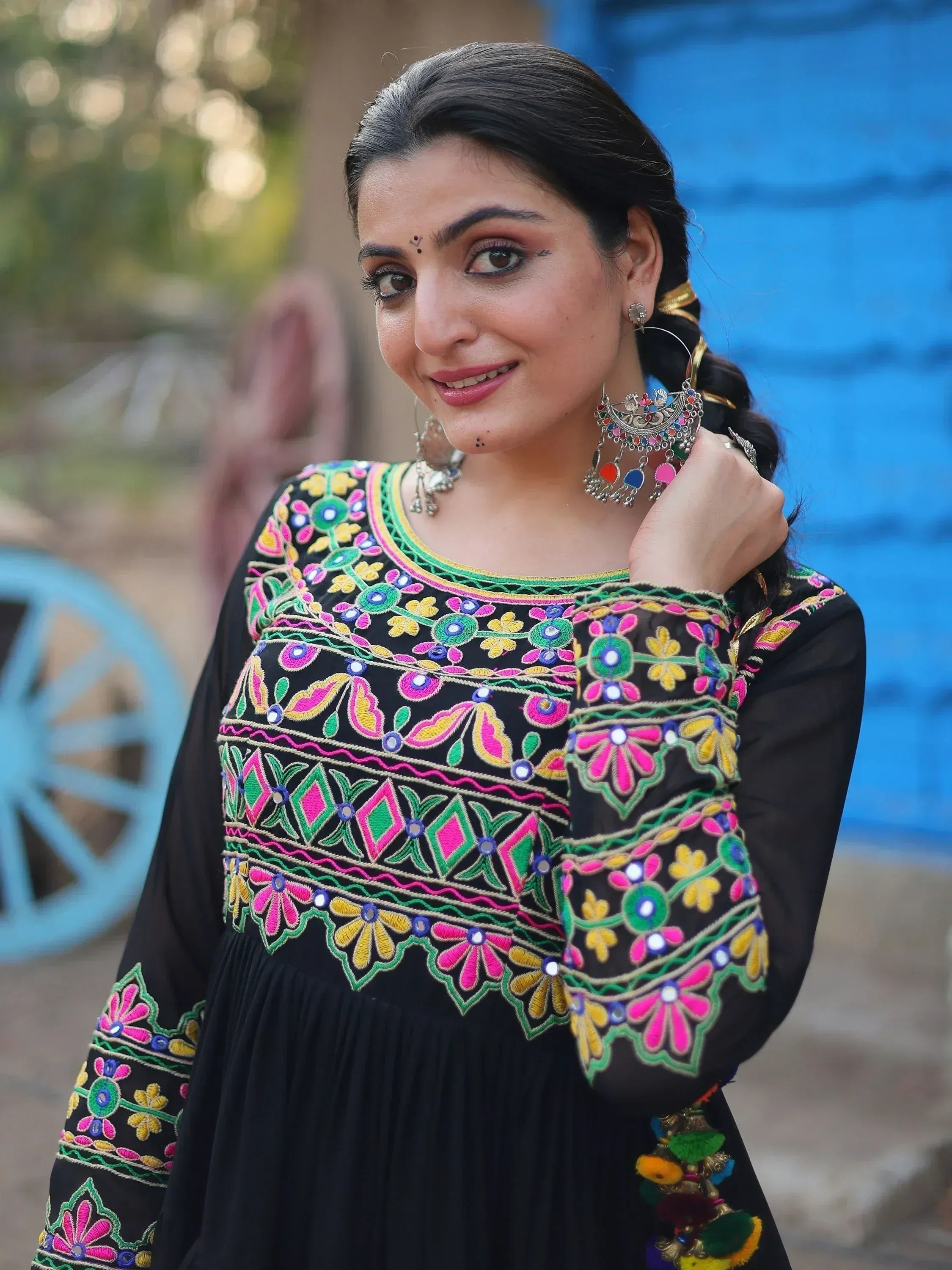 Black ethnic gown with vibrant floral embroidery and mirror work, paired with traditional jewelry