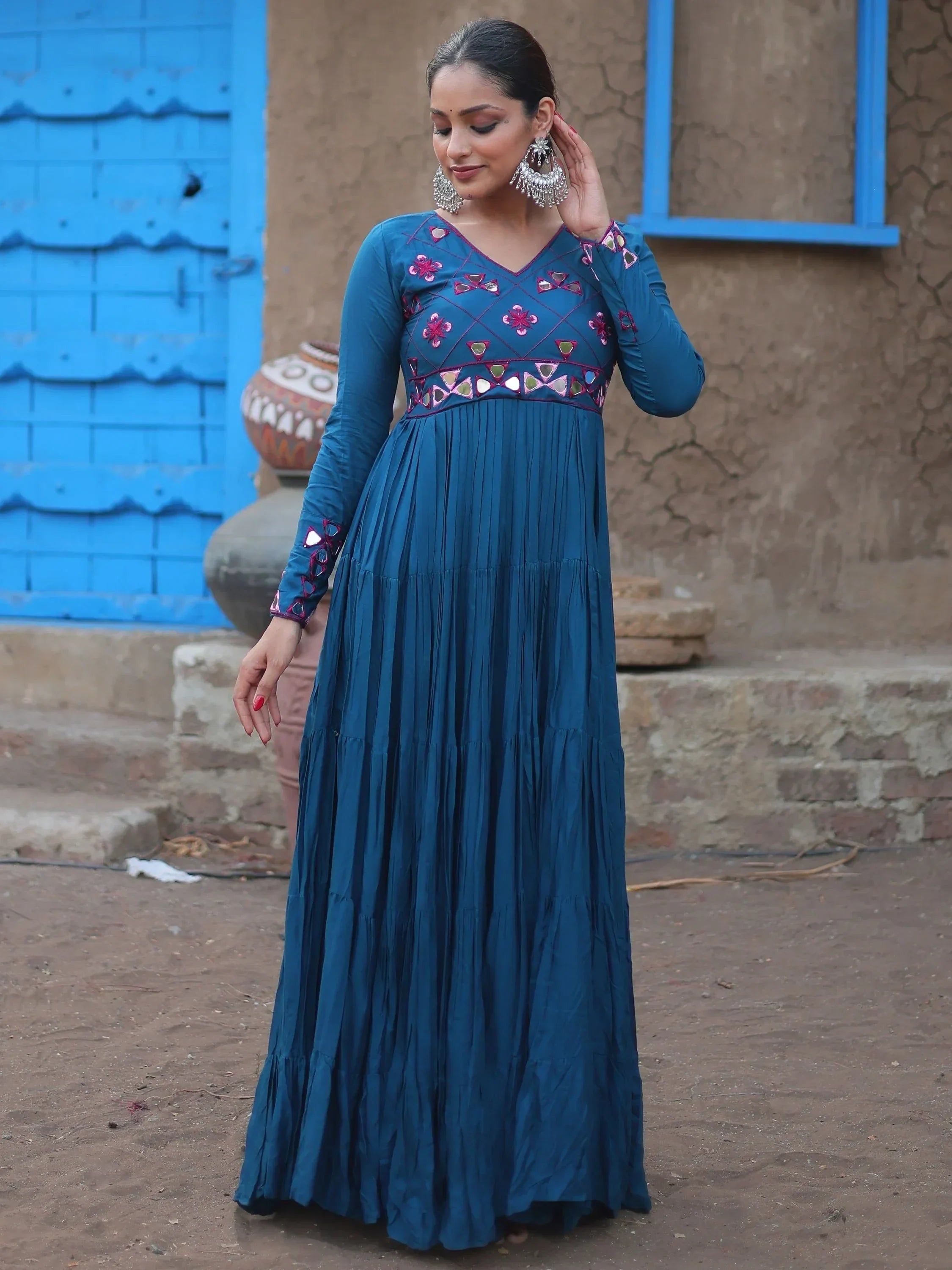 Woman in blue ethnic gown with mirror work and floral embroidery, standing outdoors