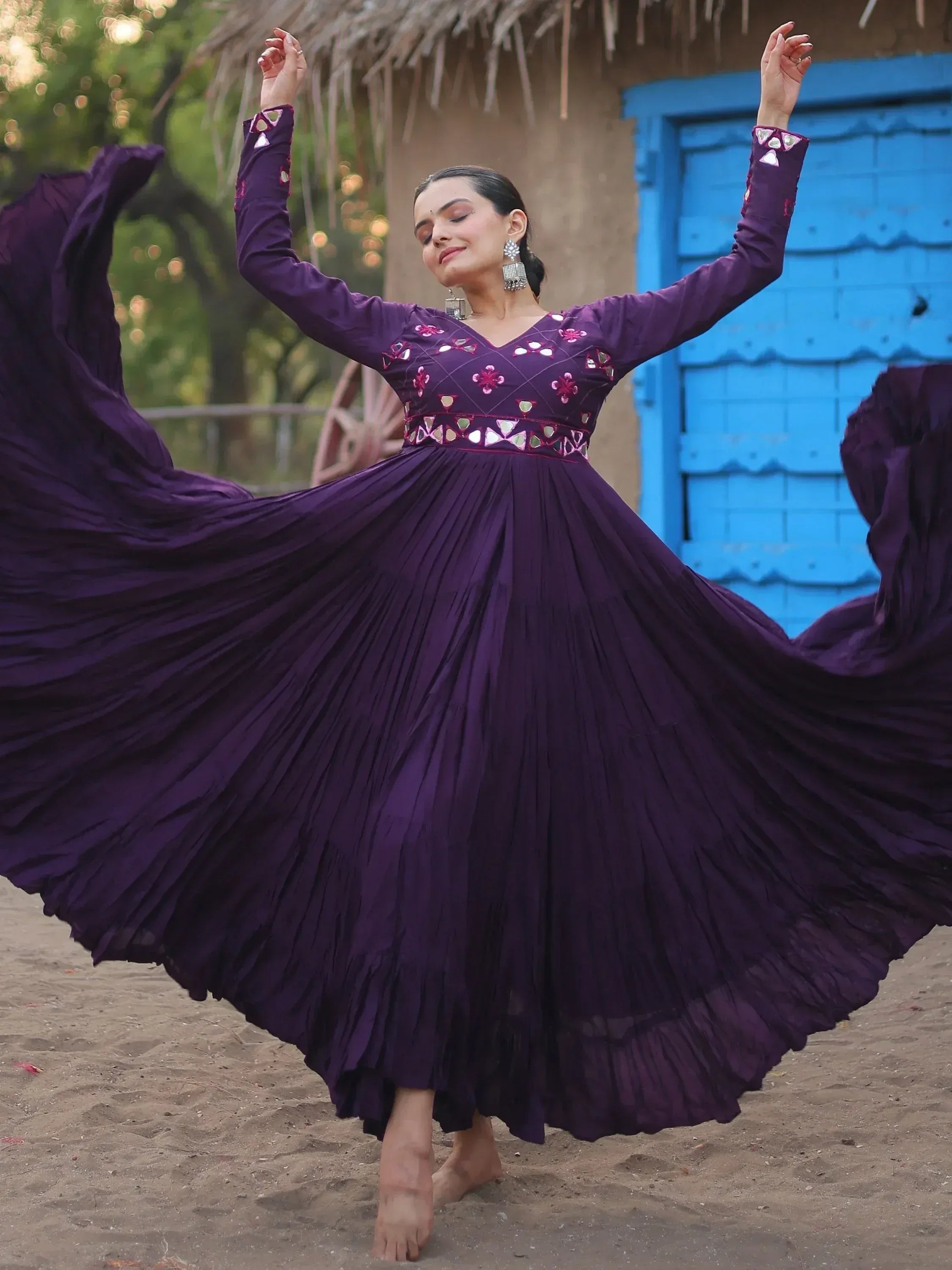 Woman twirling in purple ethnic gown with mirror work, perfect for Indian festive occasions.