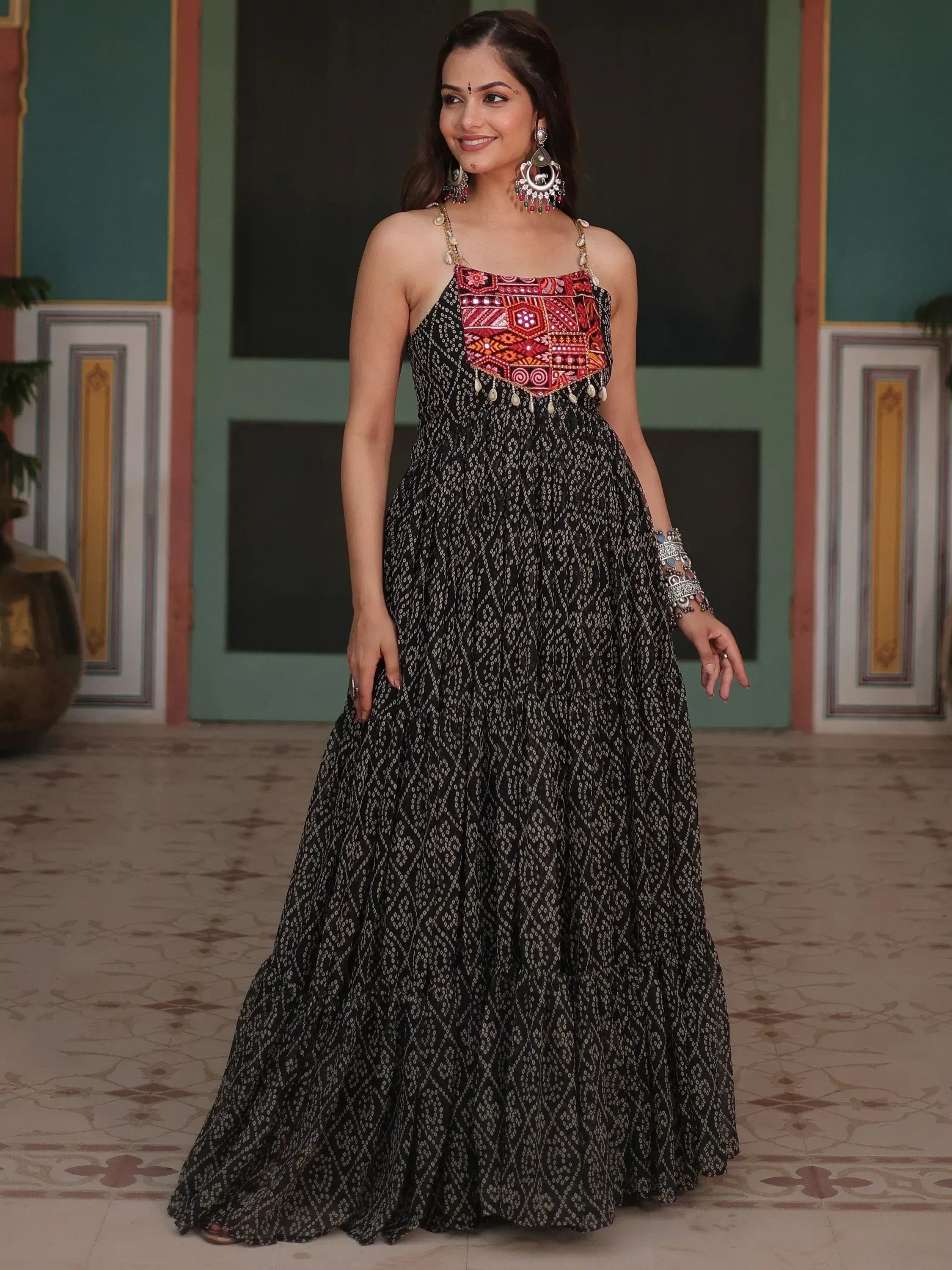 Woman in black printed ethnic gown with red mirror work, perfect for Indian festive occasions.