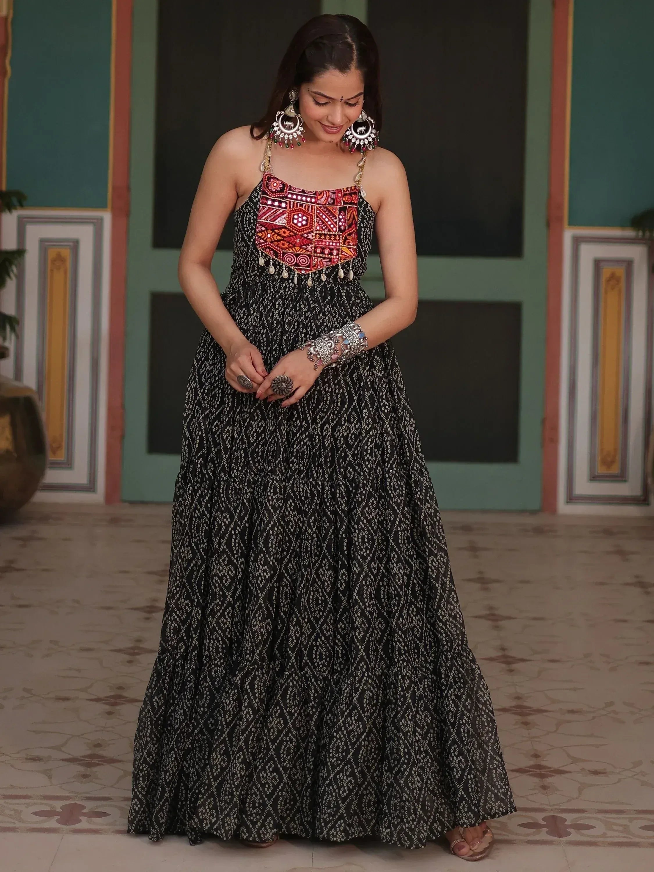 Woman in black printed ethnic gown with red embroidery, traditional jewelry, and statement earrings