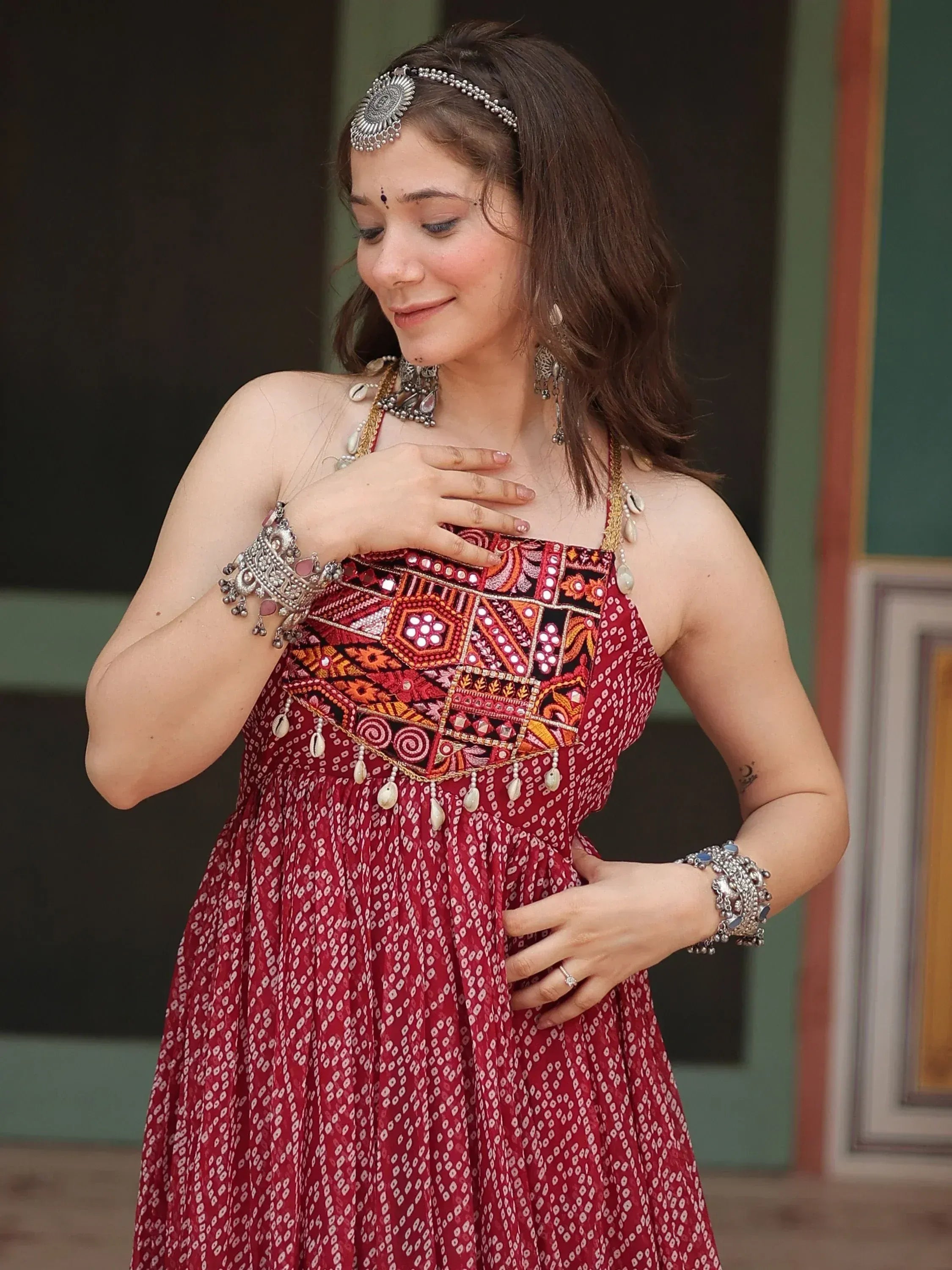 Woman in red ethnic gown with mirror work, traditional jewelry, and headpiece for Indian festive wear