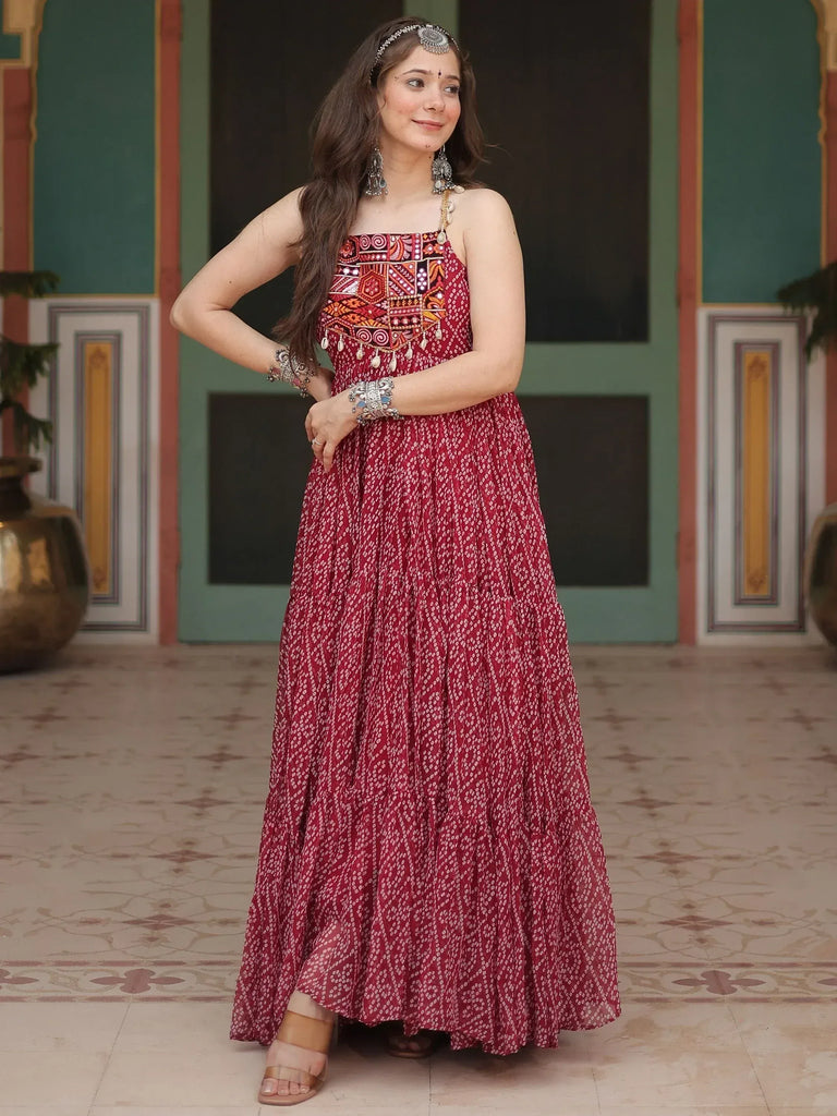 Woman in maroon ethnic gown with mirror work, paired with traditional jewelry and headpiece