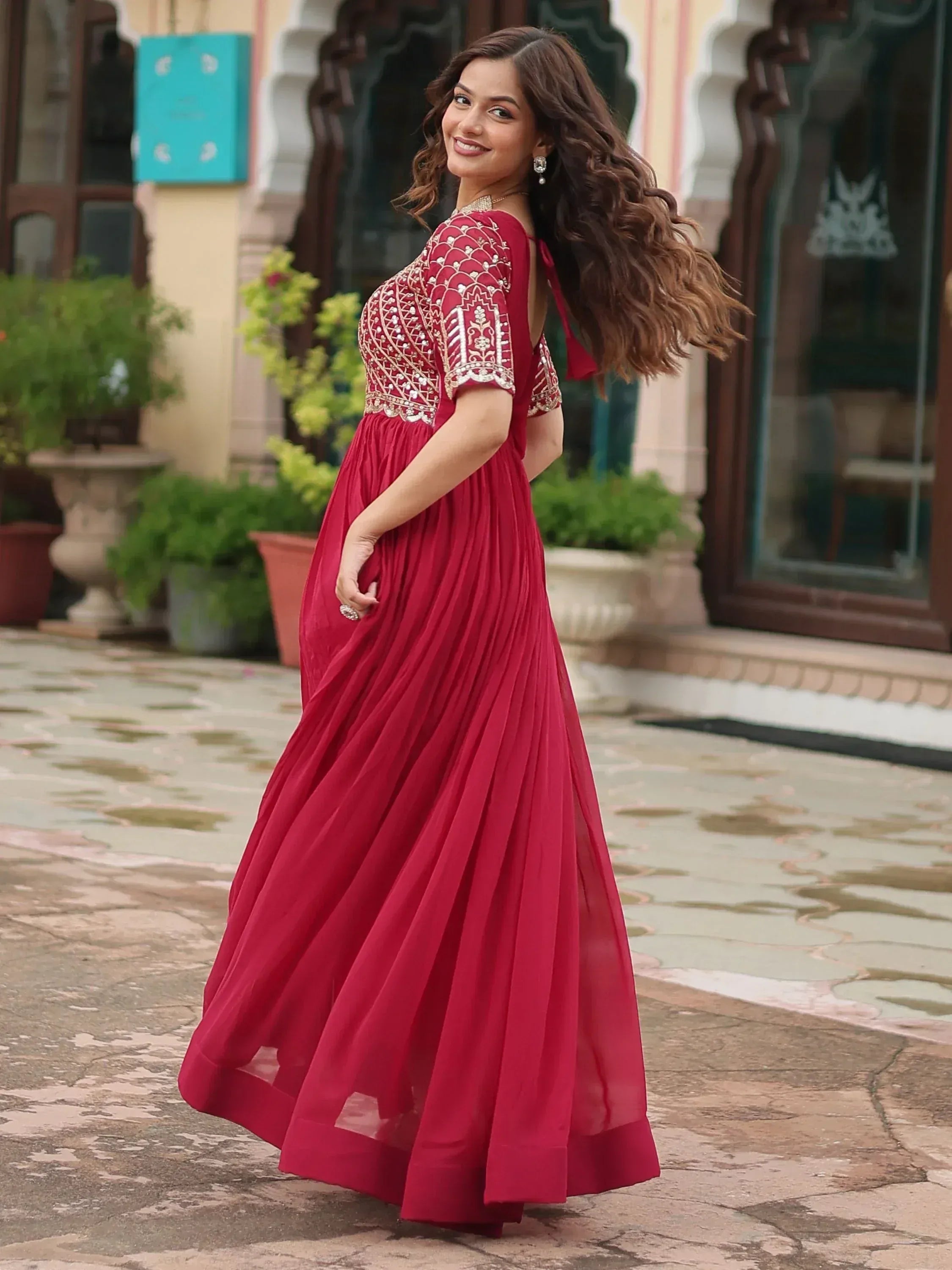 Woman in red embroidered ethnic gown with pleated skirt, perfect for Indian occasions