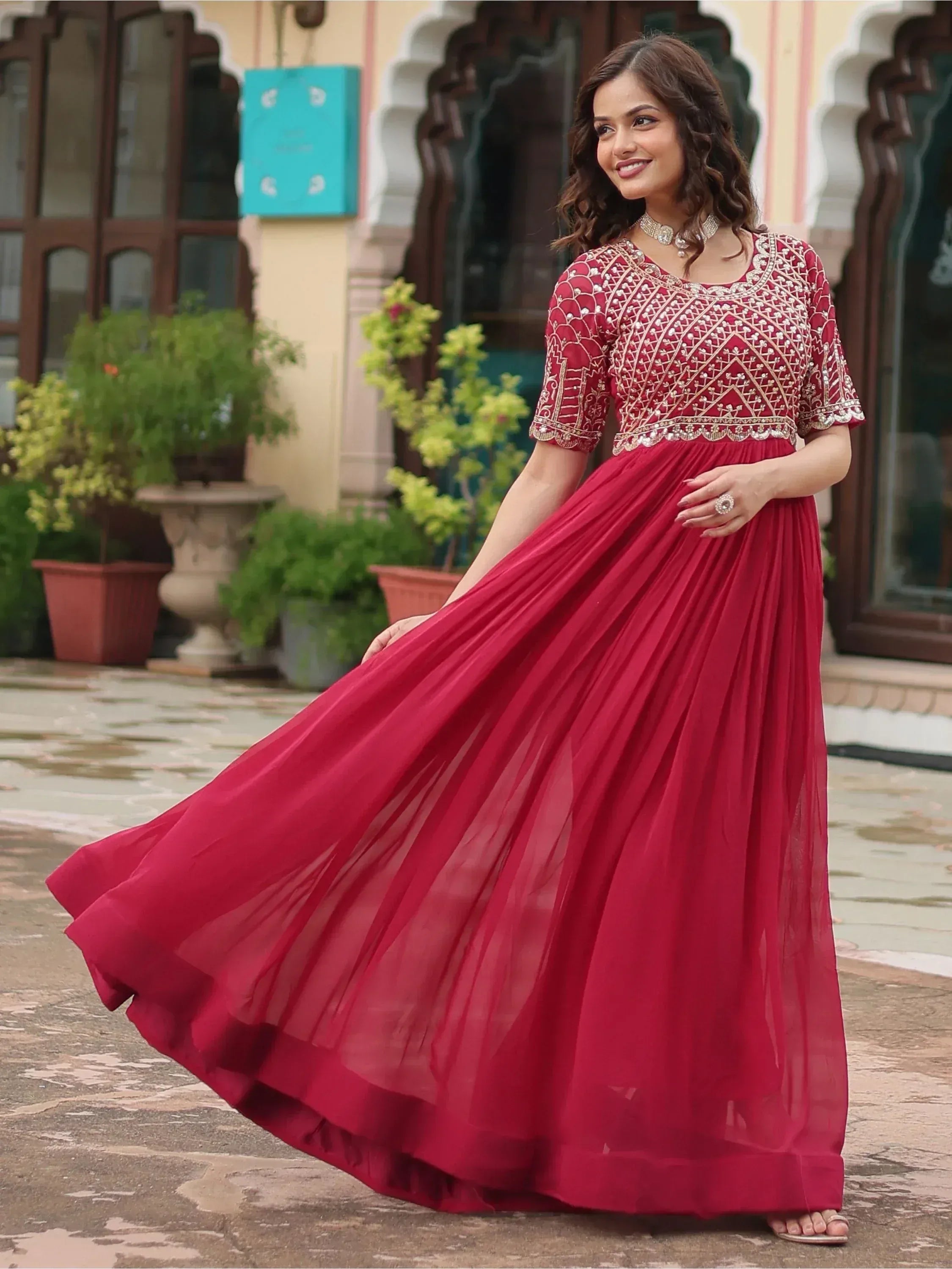 Woman in maroon ethnic gown with gold embroidery, perfect for Indian weddings and festive occasions
