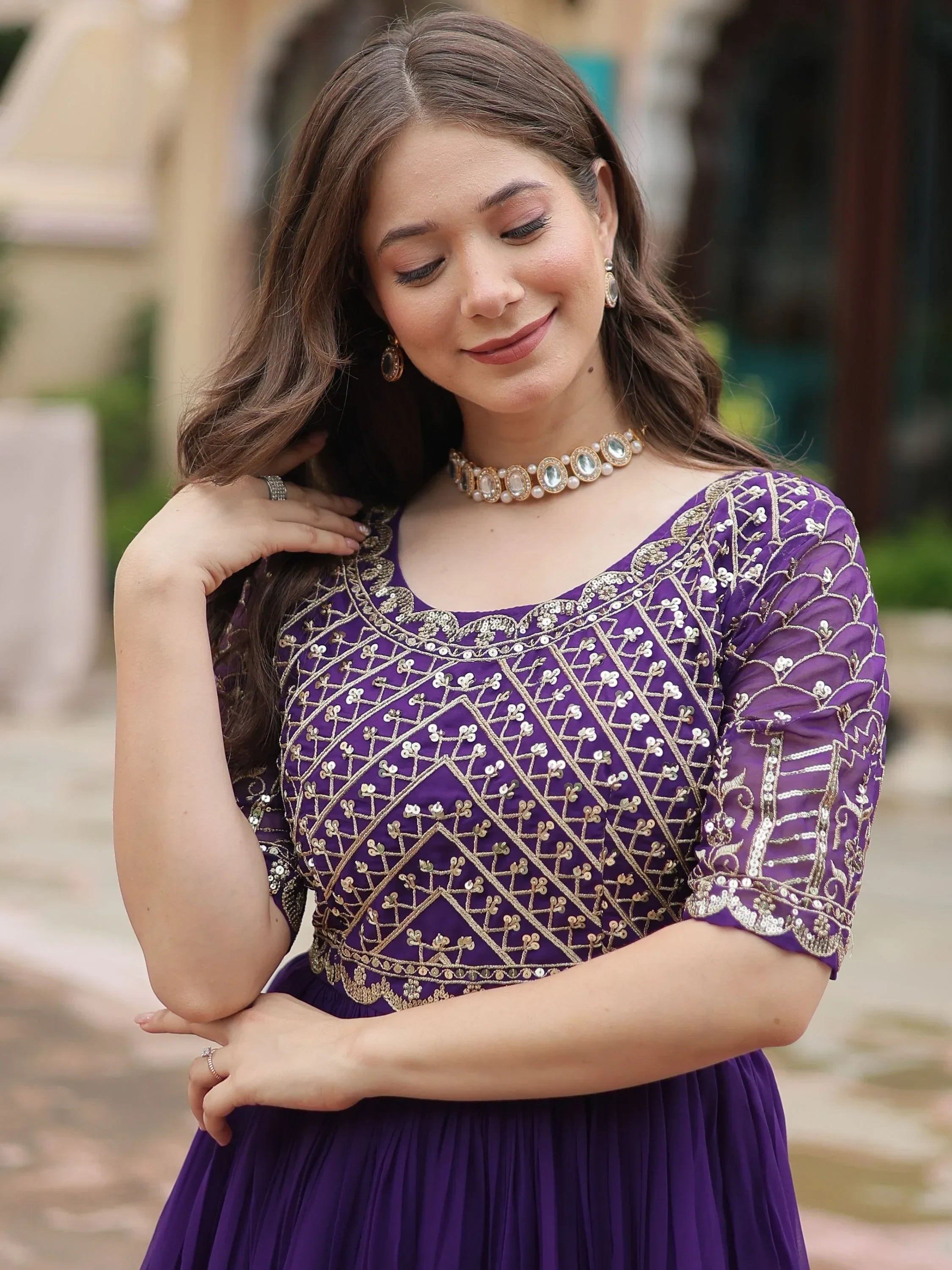 Woman in a purple embroidered ethnic gown with gold detailing, jewelry, outdoor setting