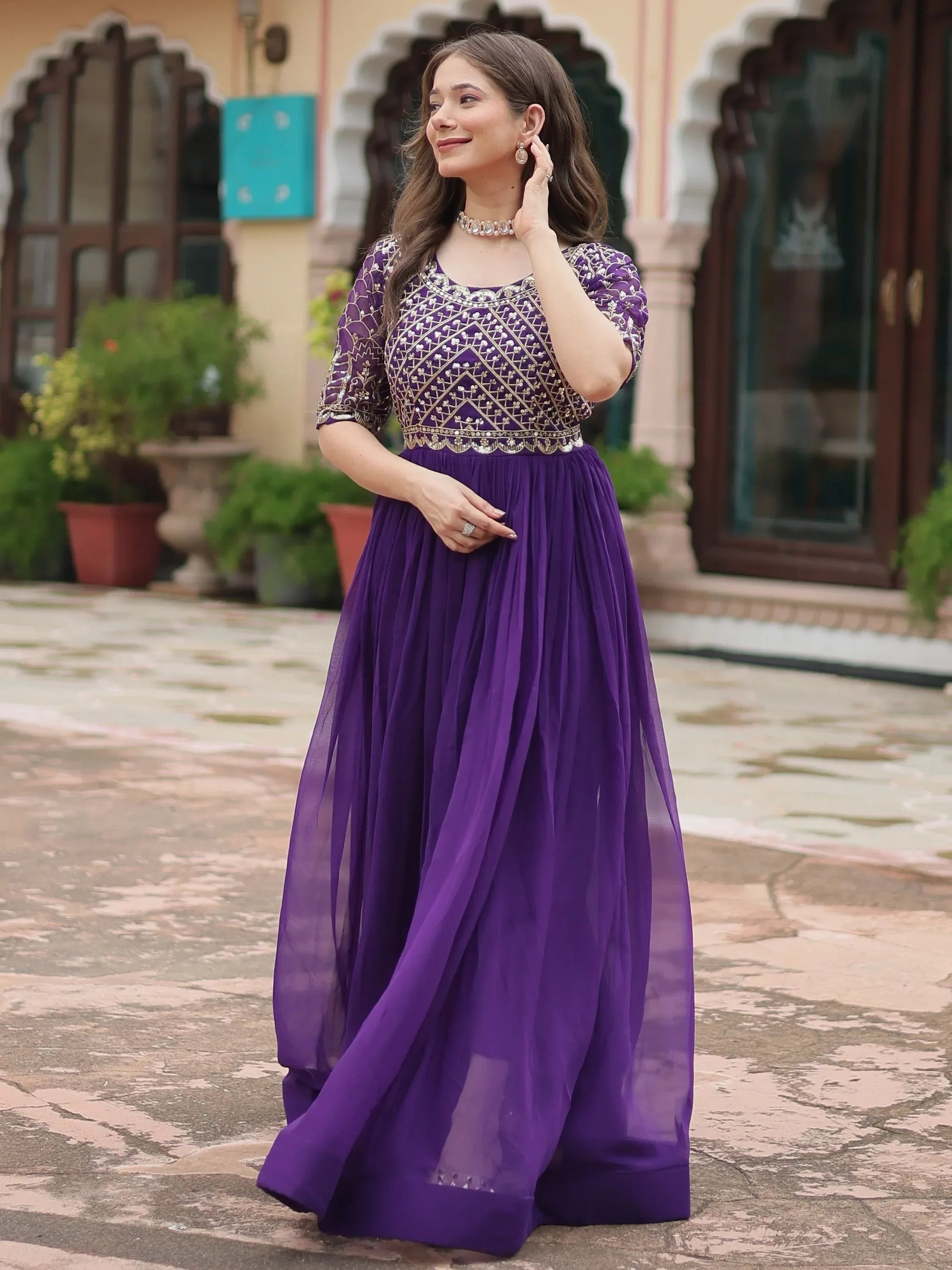 Woman in a purple embroidered ethnic gown with sheer skirt, posing outdoors