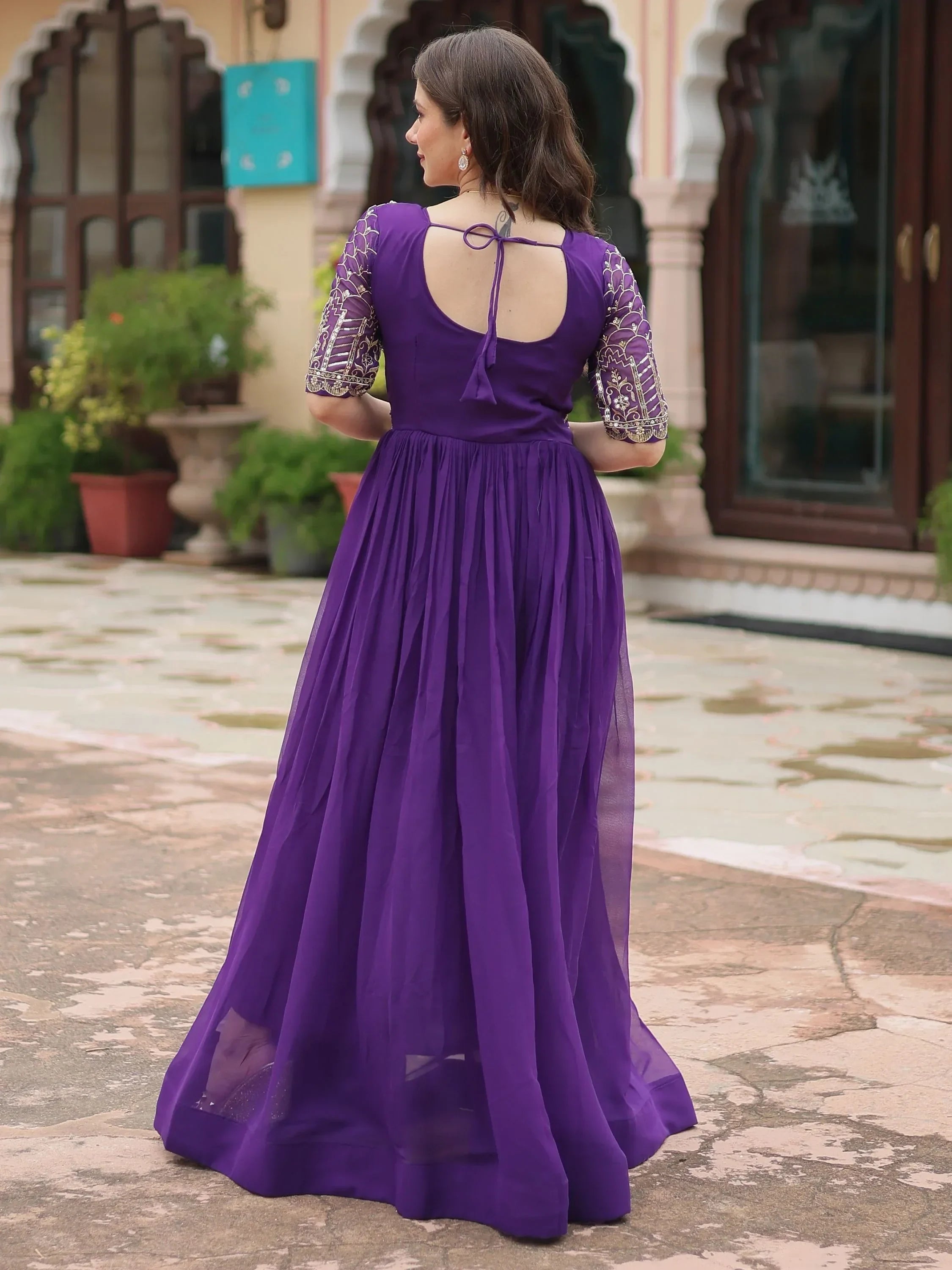 Woman in purple embroidered ethnic gown with open back, standing outdoors
