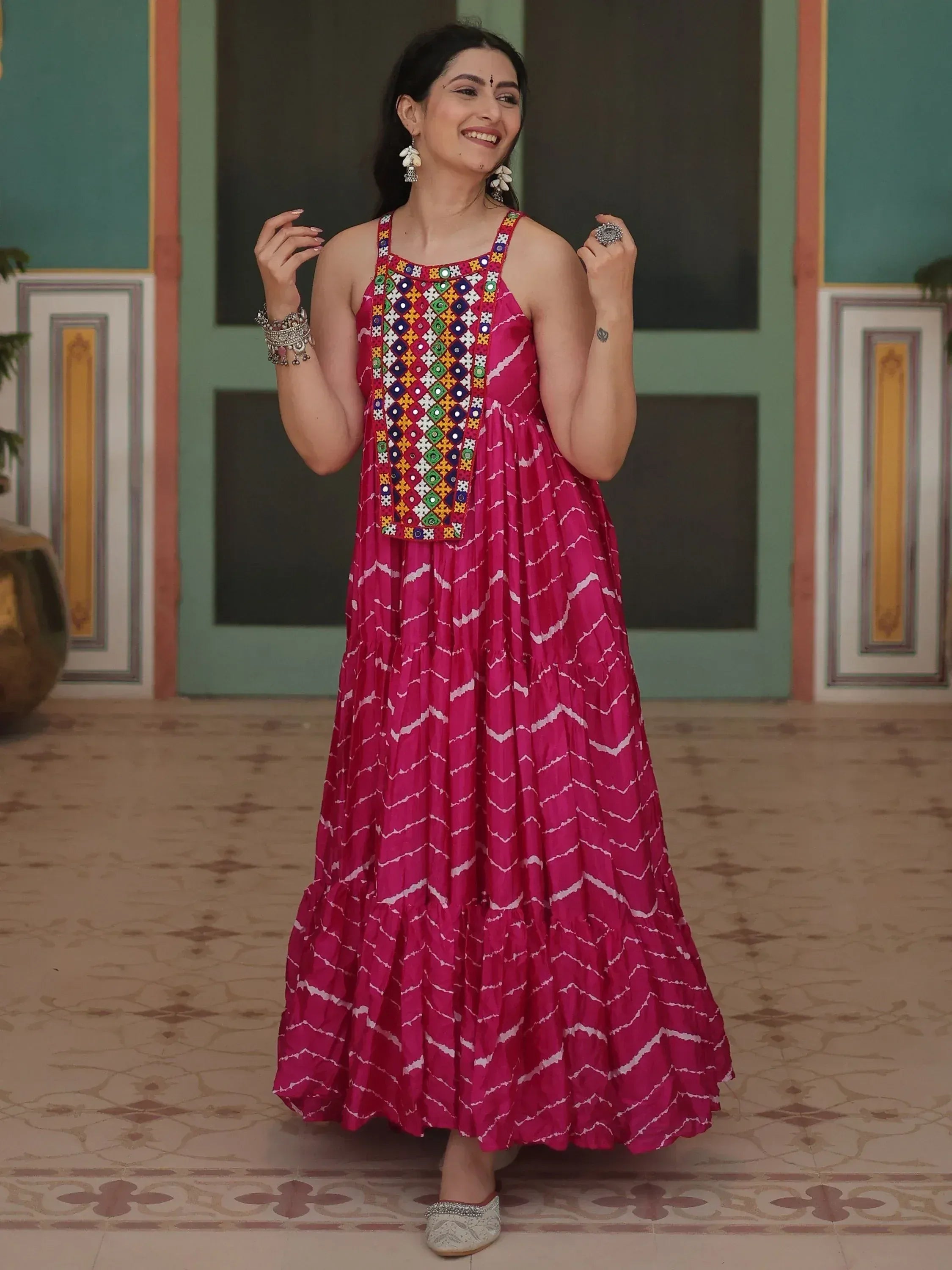 Pink ethnic gown with mirror work and zigzag print, styled with traditional jewelry for festive occasions
