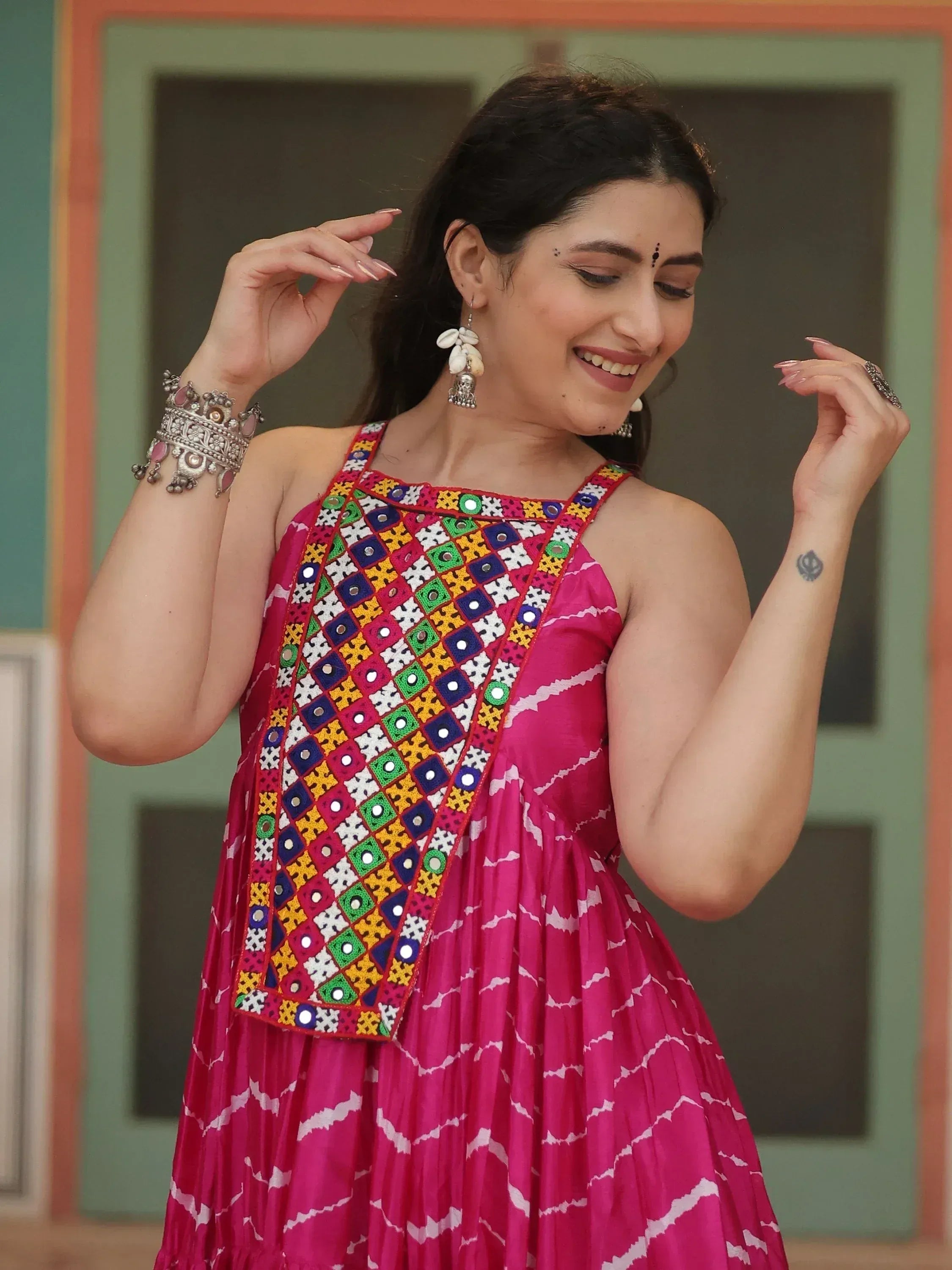 Pink ethnic gown with colorful mirror work and traditional jewelry for festive occasions