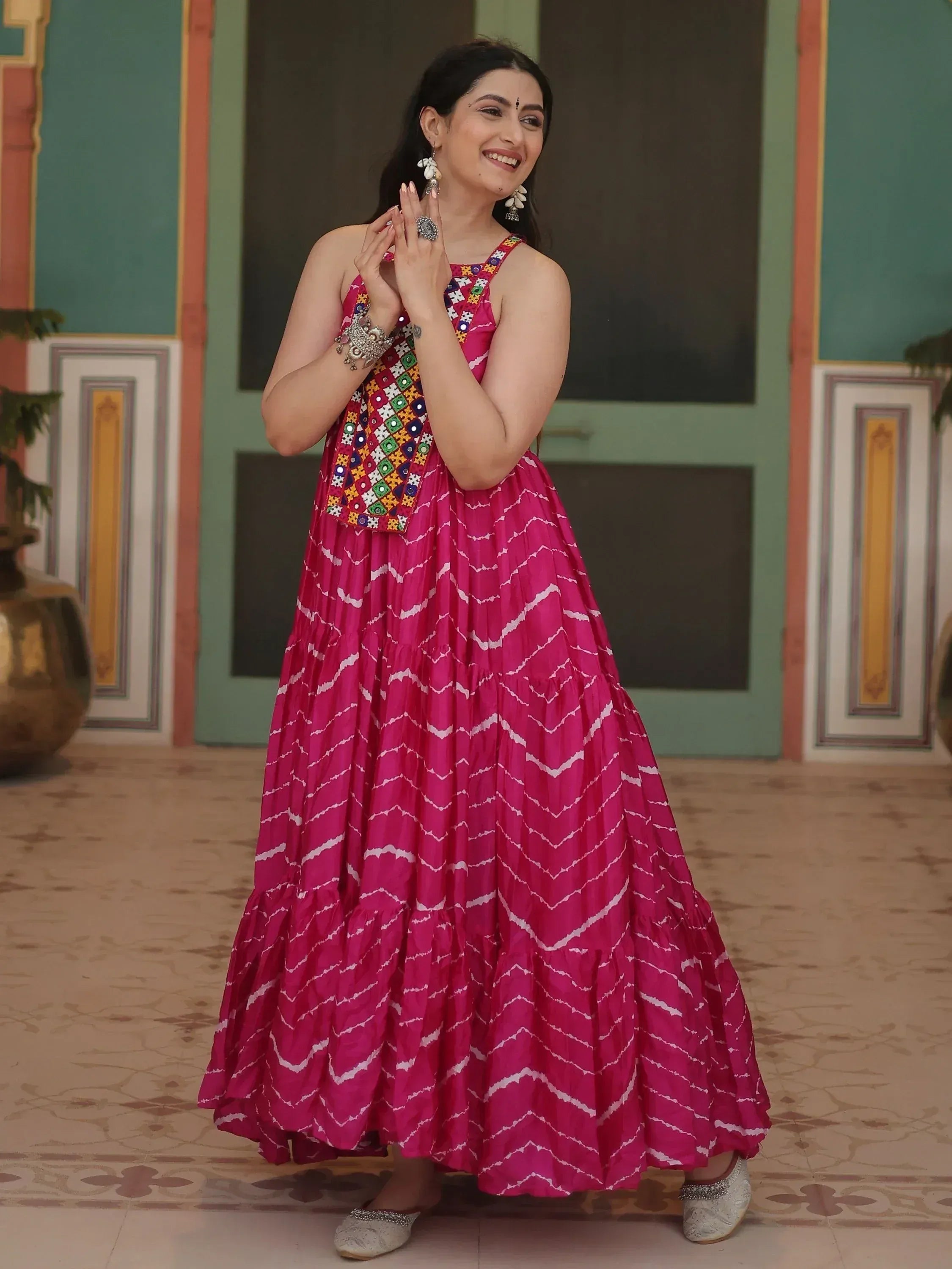 Pink ethnic gown with mirror work and zigzag print, styled with traditional jewelry for festive occasions