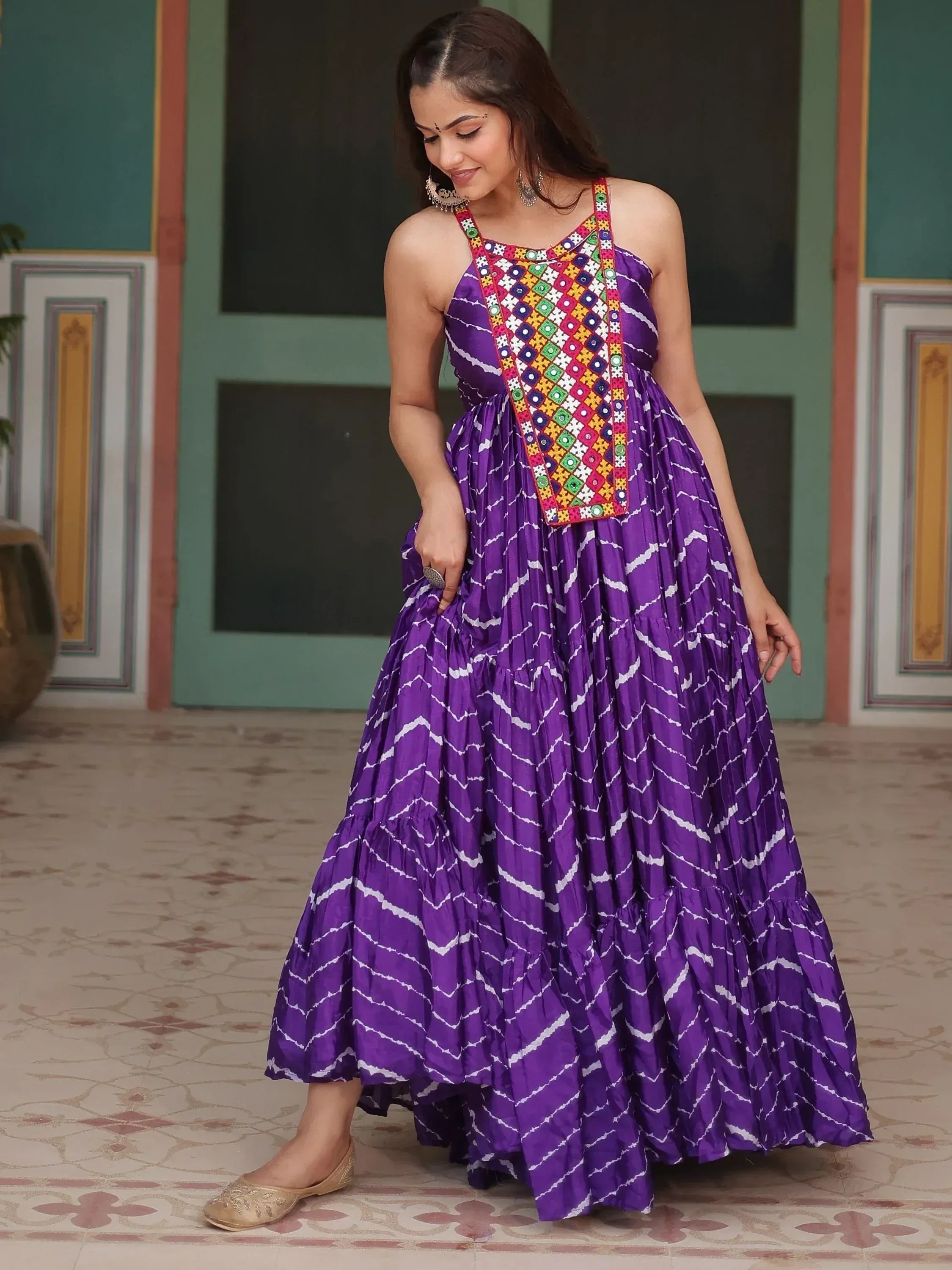 Purple ethnic gown with mirror work and tie-dye print, styled with juttis for festive occasions