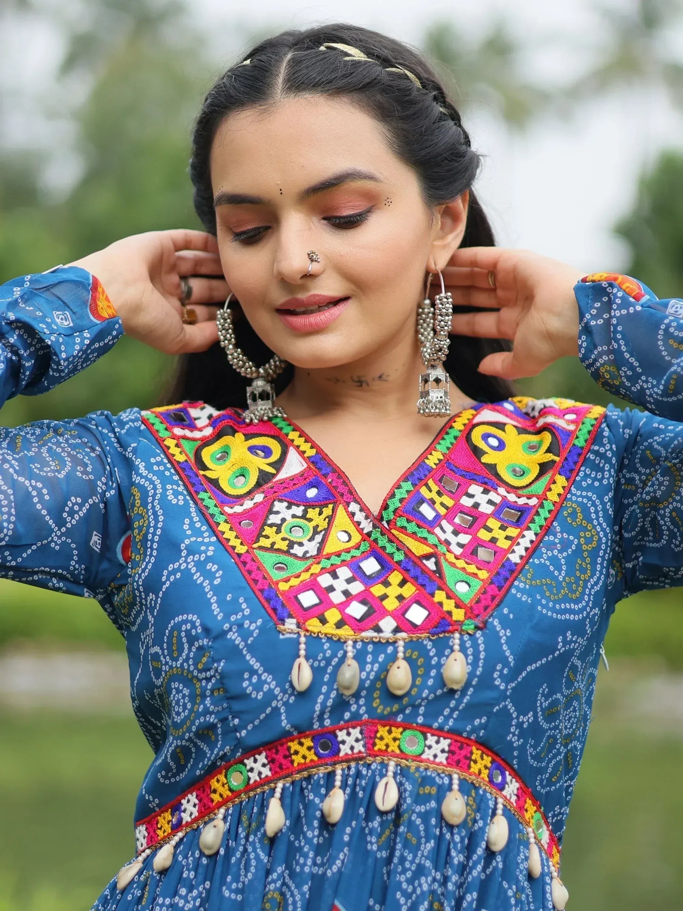 Blue ethnic gown with vibrant mirror work and shell embellishments, paired with traditional earrings